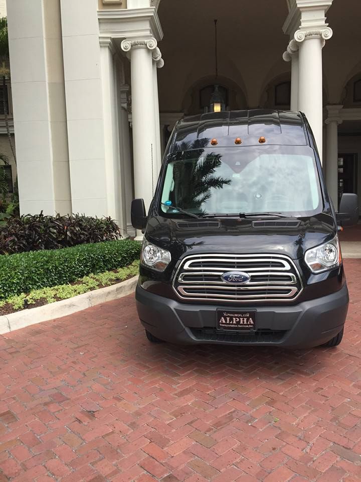 Black van parked under a covered entrance with white columns and brick paving.