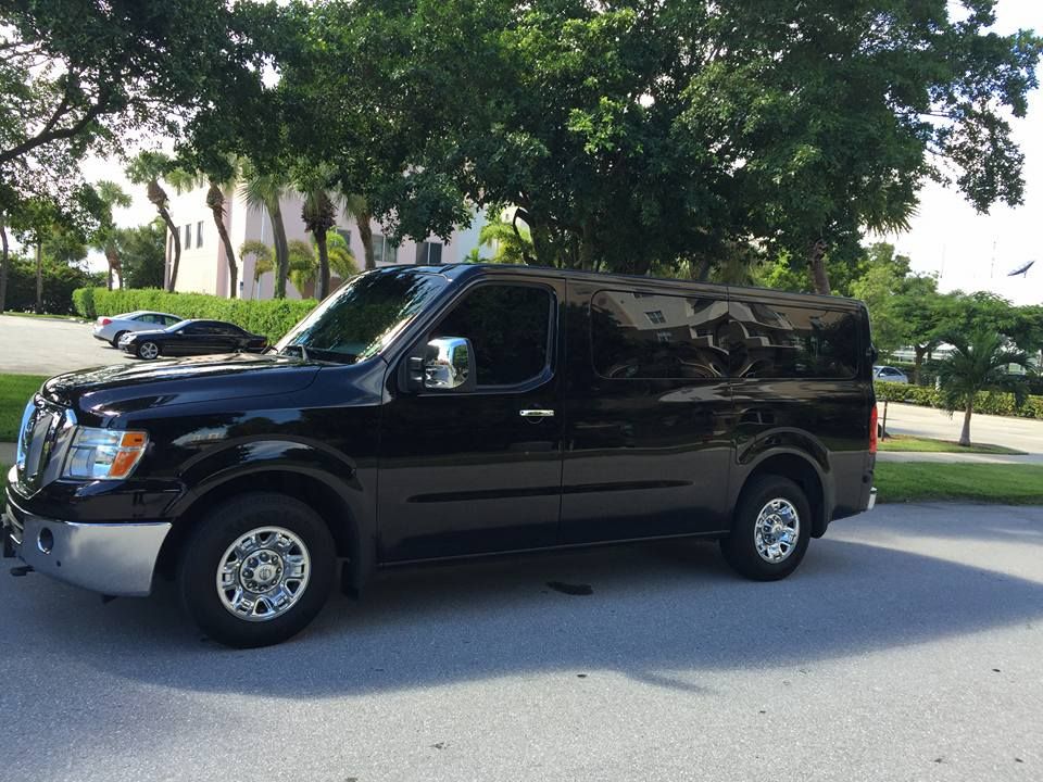 Black passenger van parked on a residential street under trees