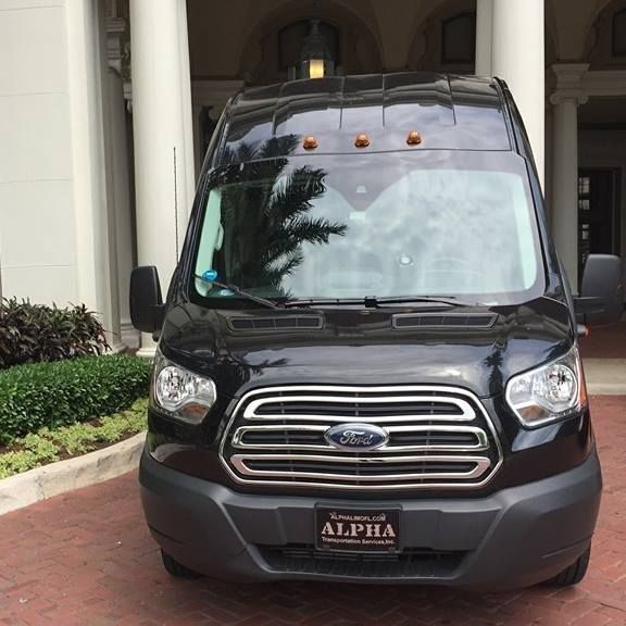 Front view of a black Ford van parked under a covered building entrance