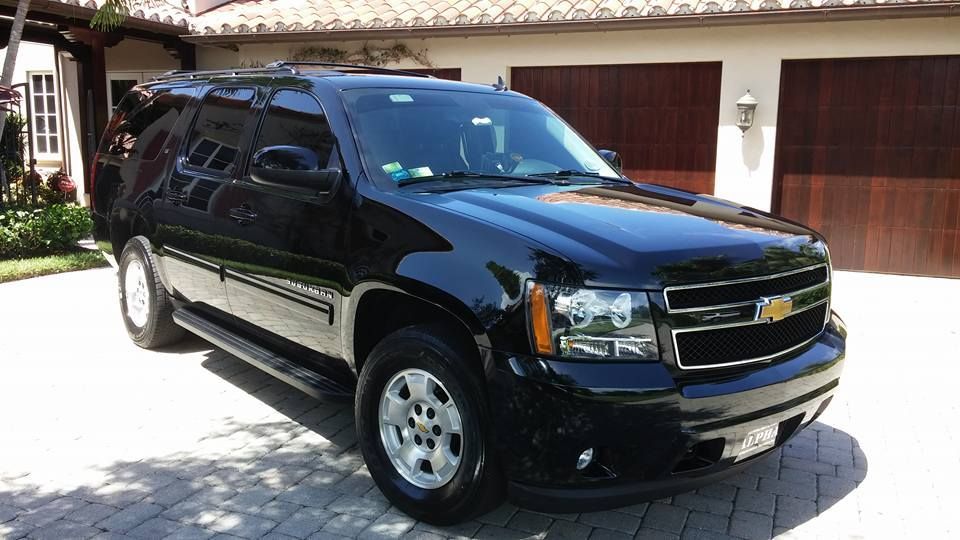 Black Chevrolet SUV parked in a driveway in front of a house with a garage