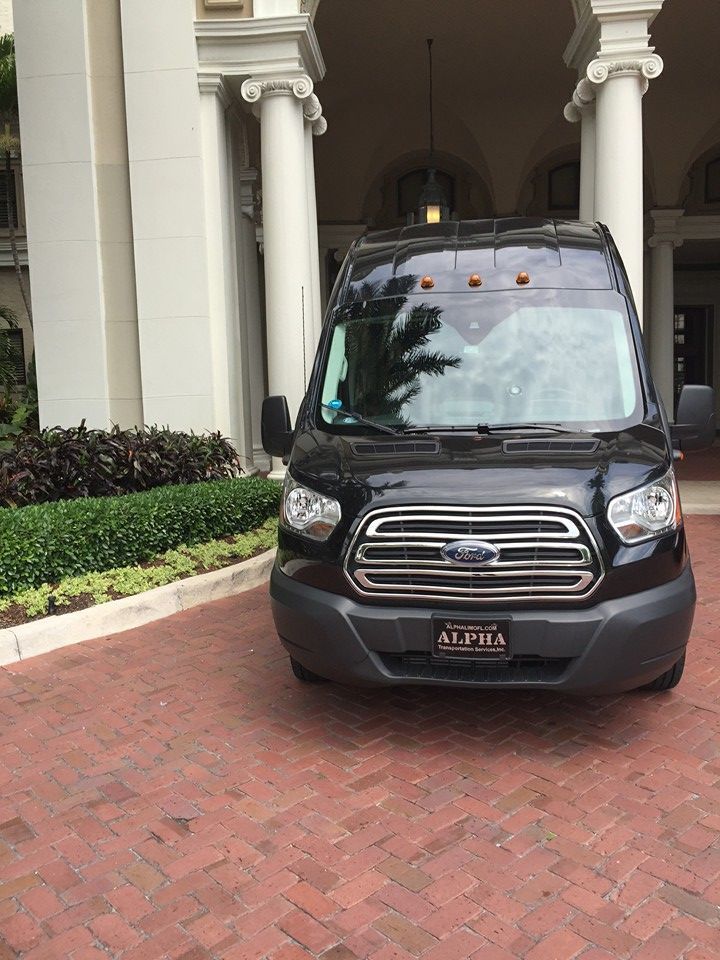 Black van parked on a red brick driveway beside a white-columned building