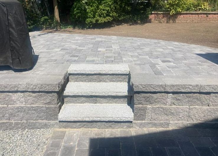 A set of stairs leading up to a patio with a grill in the background.