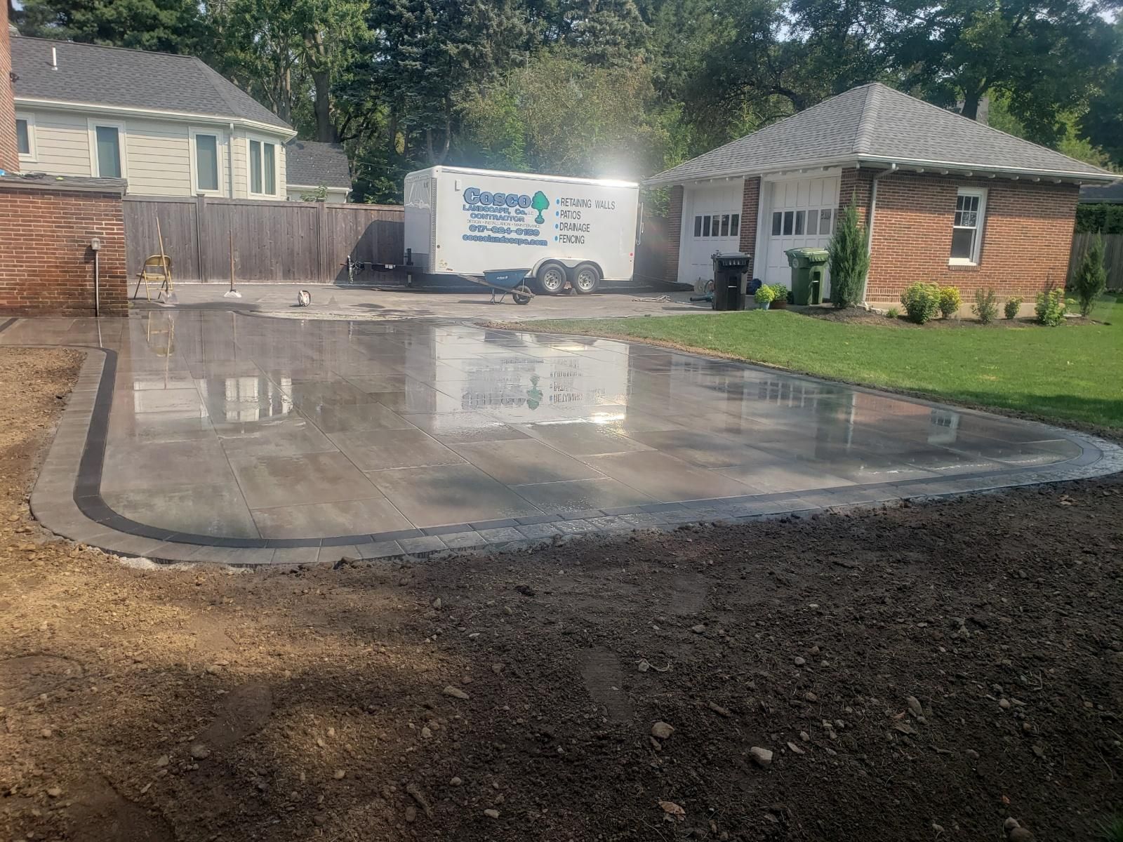 A white trailer is parked in a driveway next to a house.