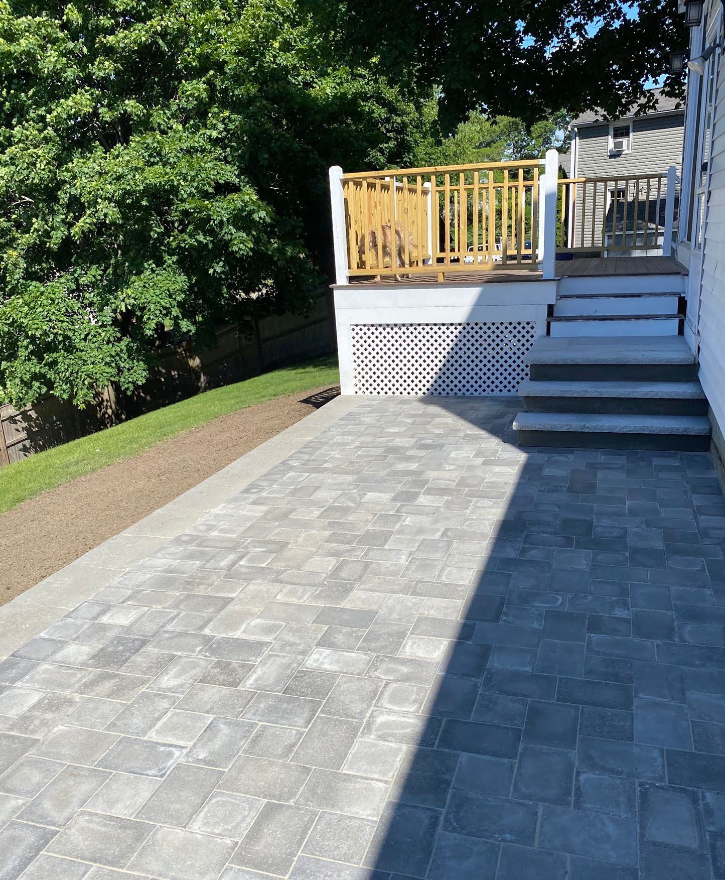 A brick walkway leading to a deck with a yellow railing