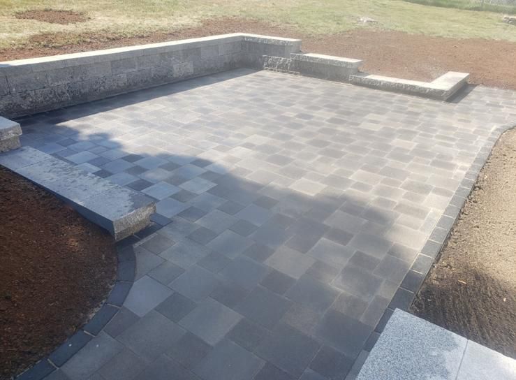A patio with a stone wall and steps leading to it.