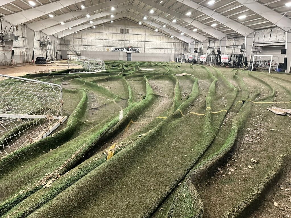 Indoor dirt track with green artificial turf barriers.