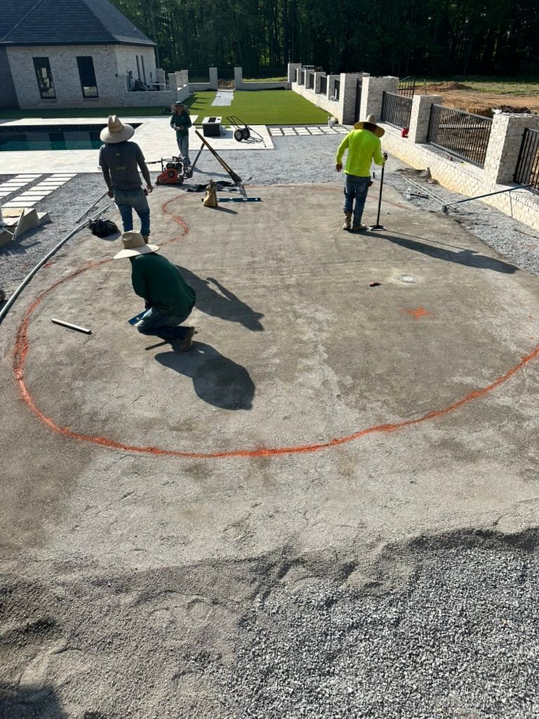 Construction workers marking a circular area for a pool in a backyard.
