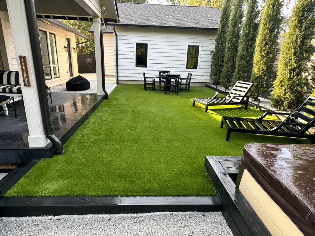 Backyard with green turf, patio furniture, lounge chairs, and a hot tub.
