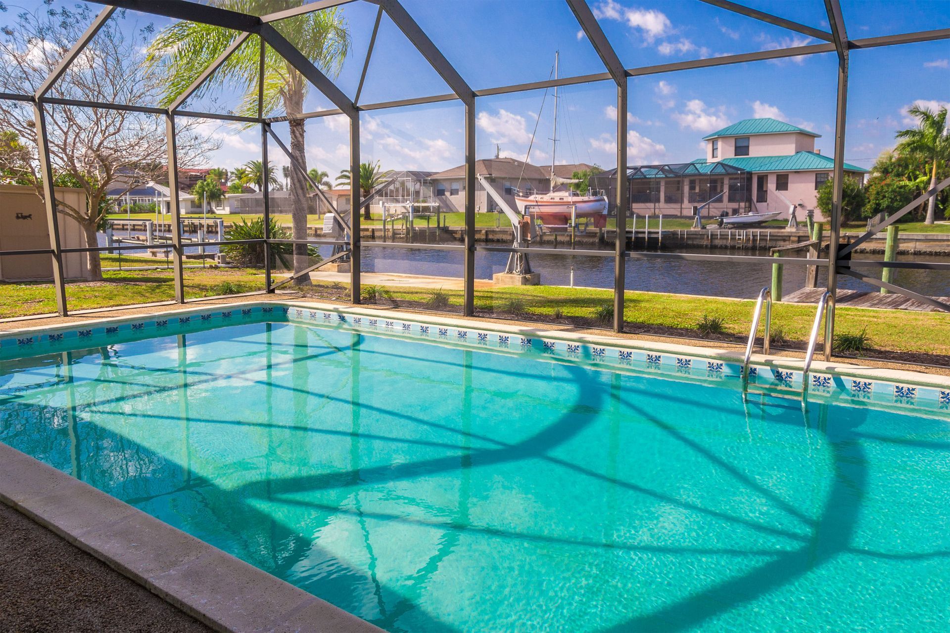 Screened-in backyard pool with turquoise water and lakeside homes in the background