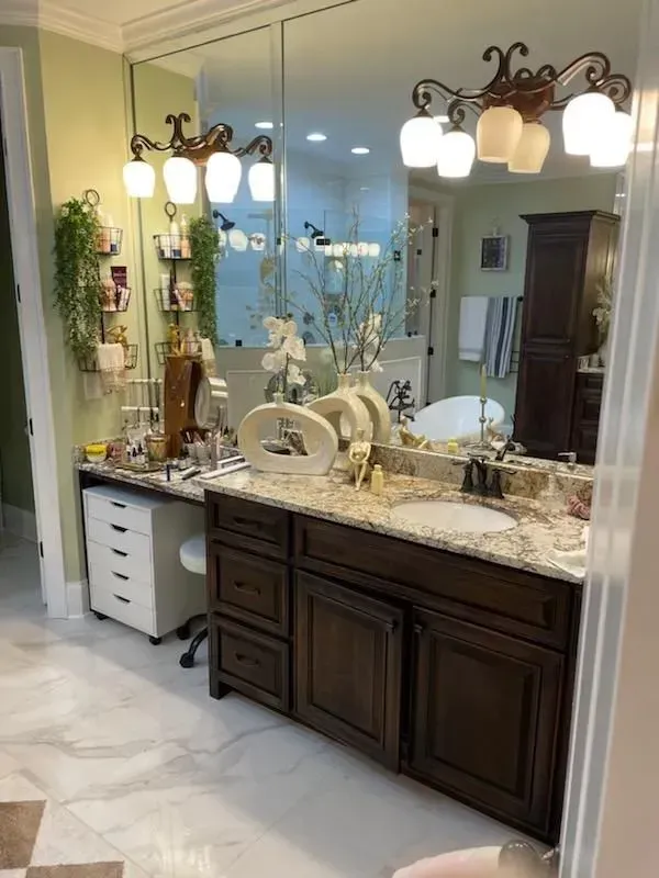 Elegant bathroom vanity with dark cabinets, marble countertop, large mirror, and hanging lights