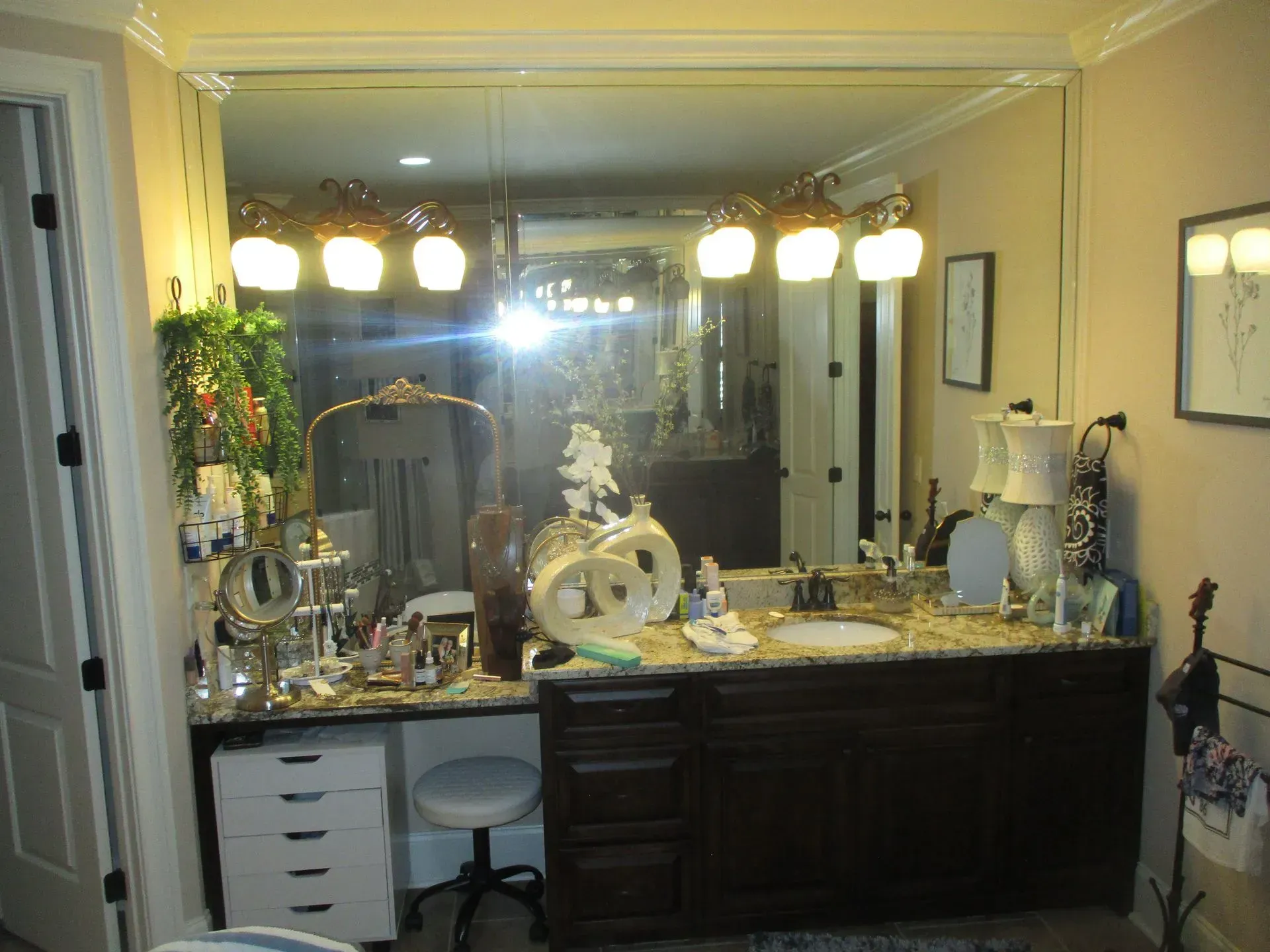 Bathroom vanity with mirror, bright lights, and toiletries on a dark wood counter.