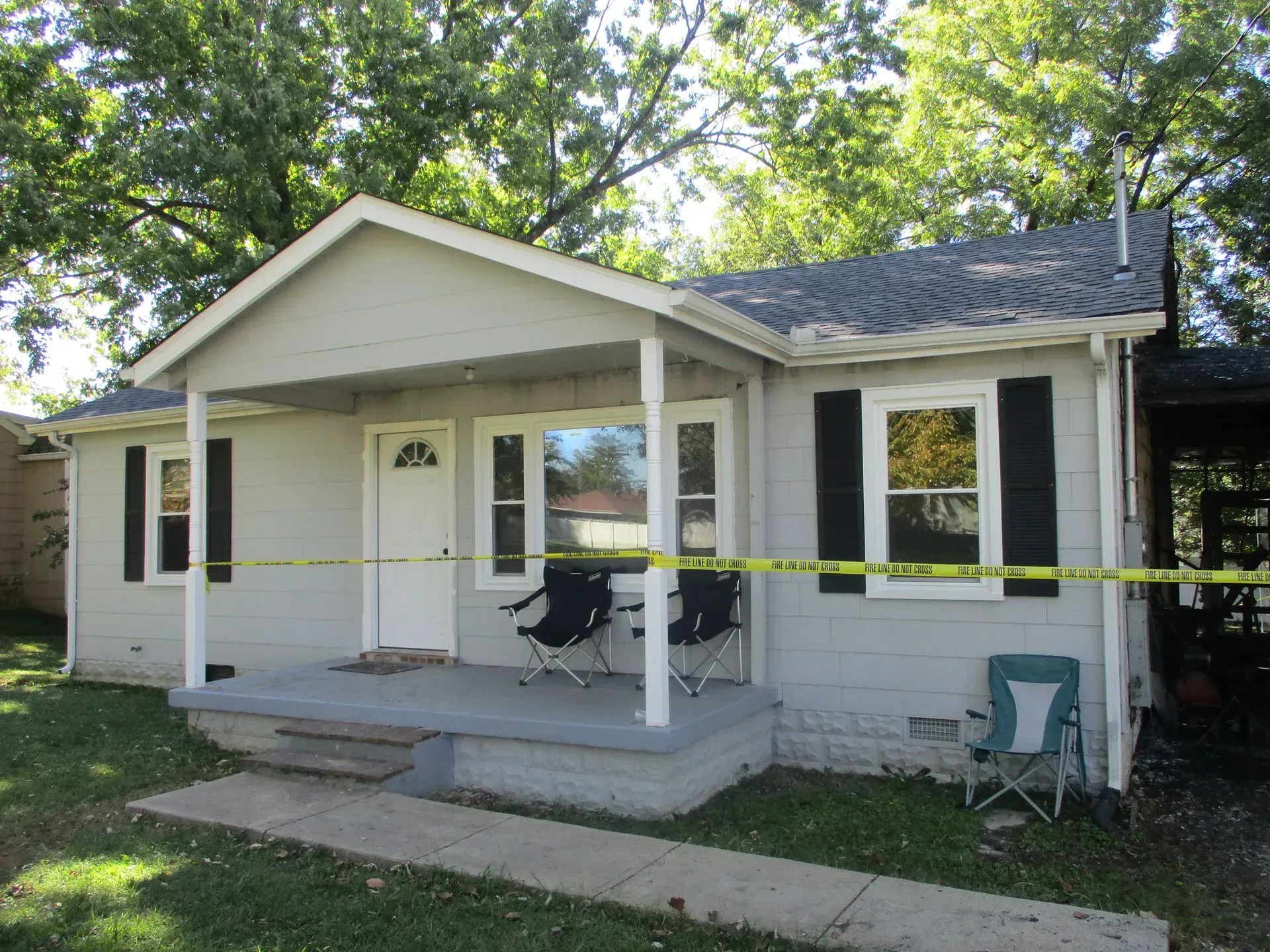 Single-story white house with yellow caution tape across the front porch and yard.