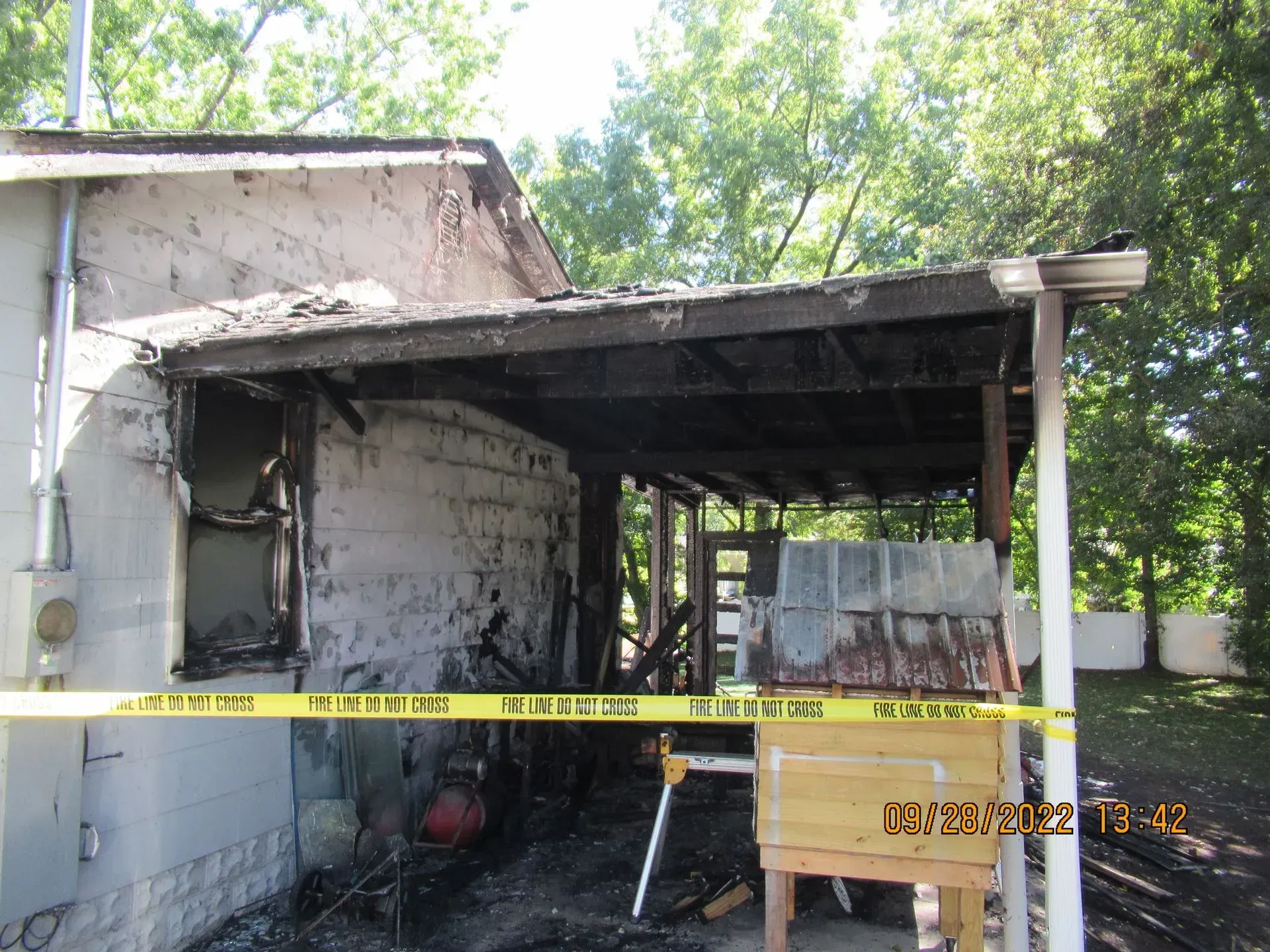 Partially collapsed garage with a damaged roof, taped off with yellow caution tape.