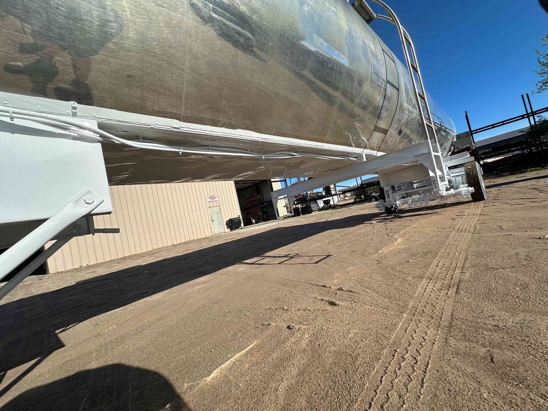 Large silver rocket on a launch pad beside a beige building under a clear blue sky
