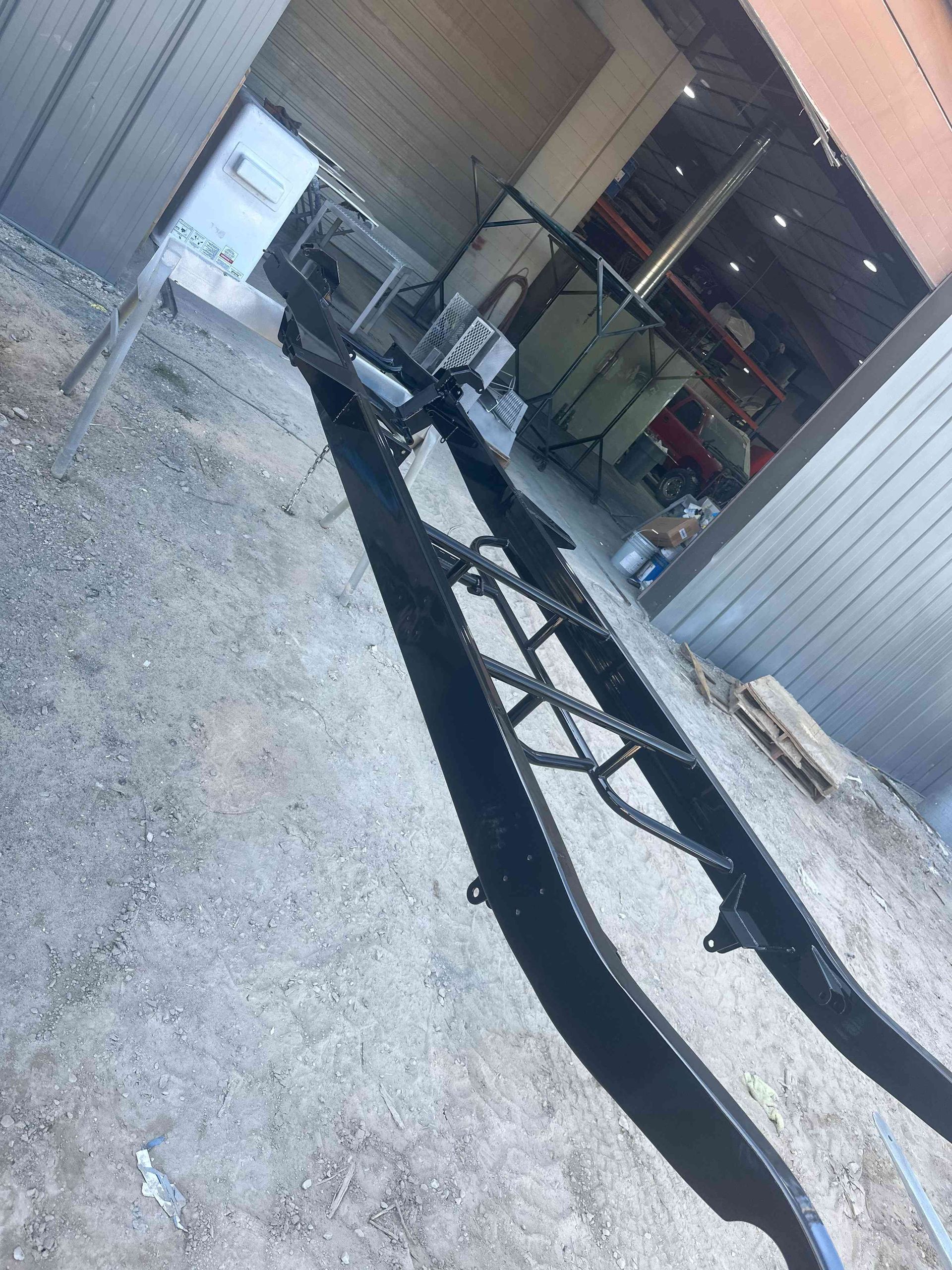 Narrow alley beside a building with snow on the ground and a long black cable or hose stretched across it