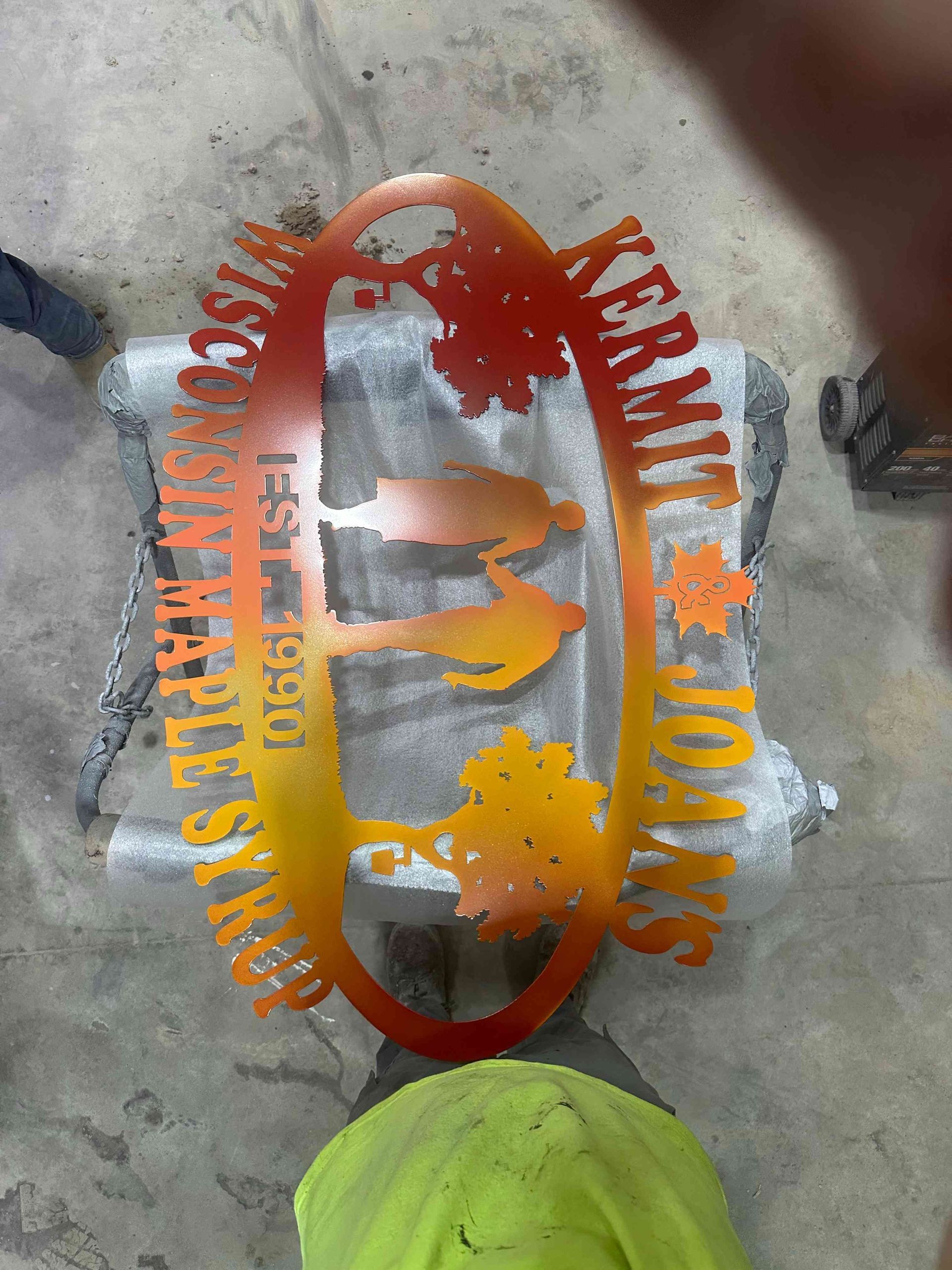 Orange logo and text painted on concrete, with a bright green object at the bottom.