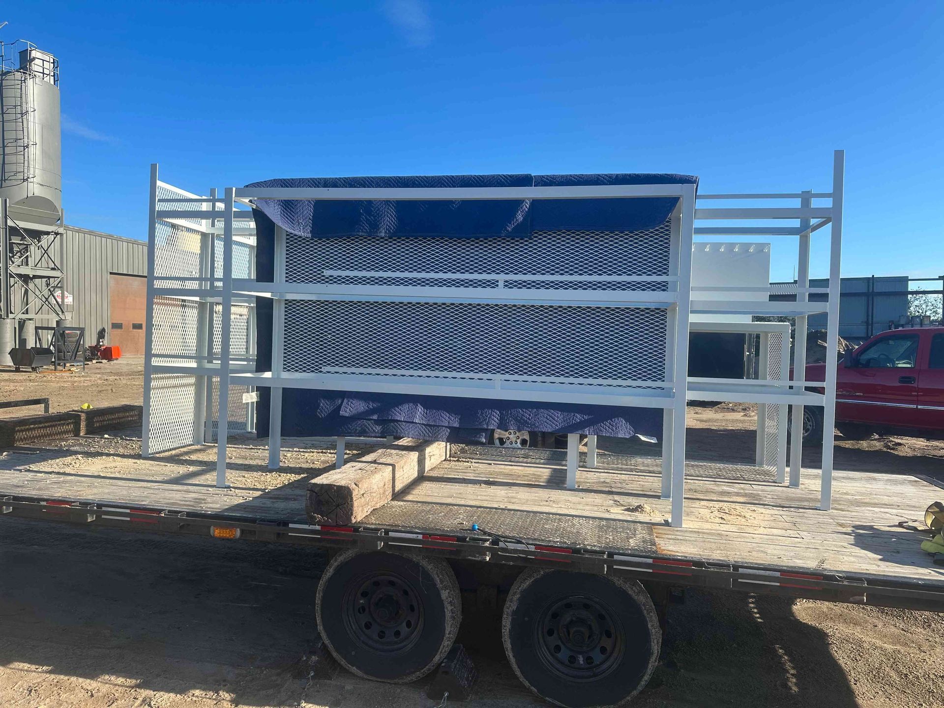 Metal rack of coiled white tubing on a trailer in an industrial yard