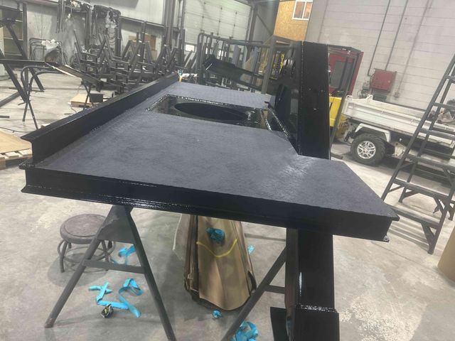 Black metal worktable with raised sides in a workshop, viewed at an angle