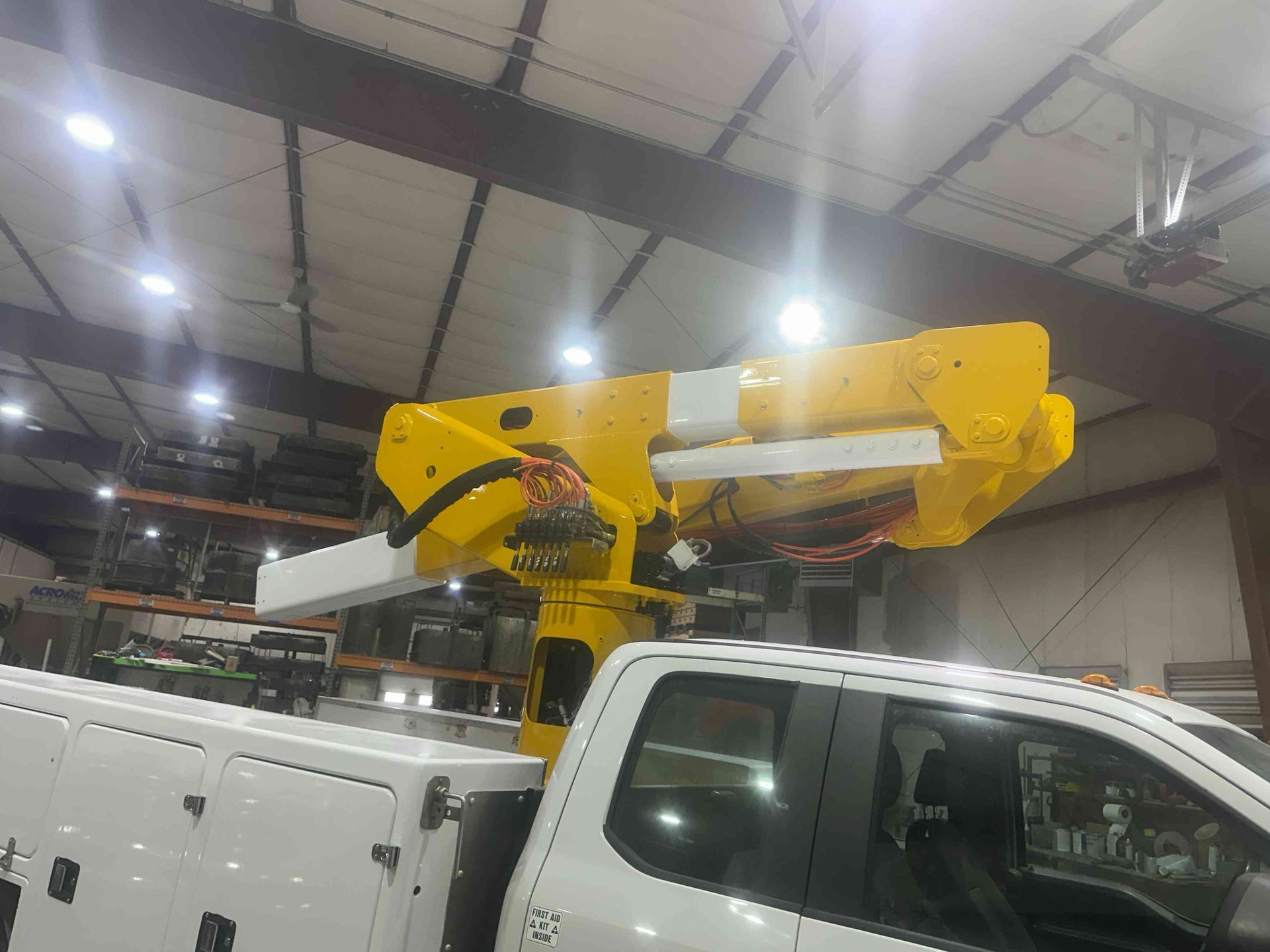 Yellow utility boom lift mounted on a white truck inside a warehouse facility