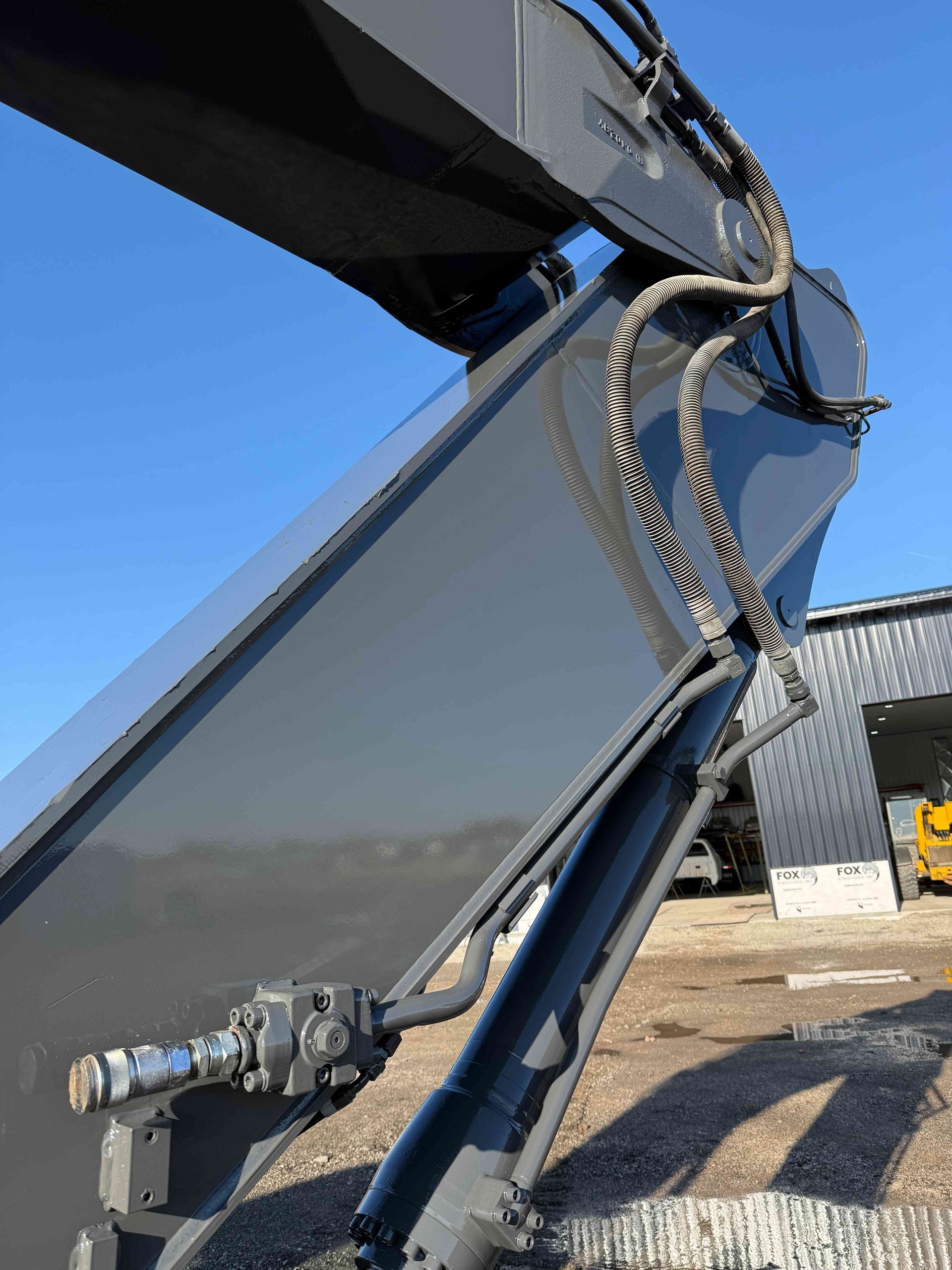 Close-up of a blue excavator arm and hydraulic mechanism on a construction site