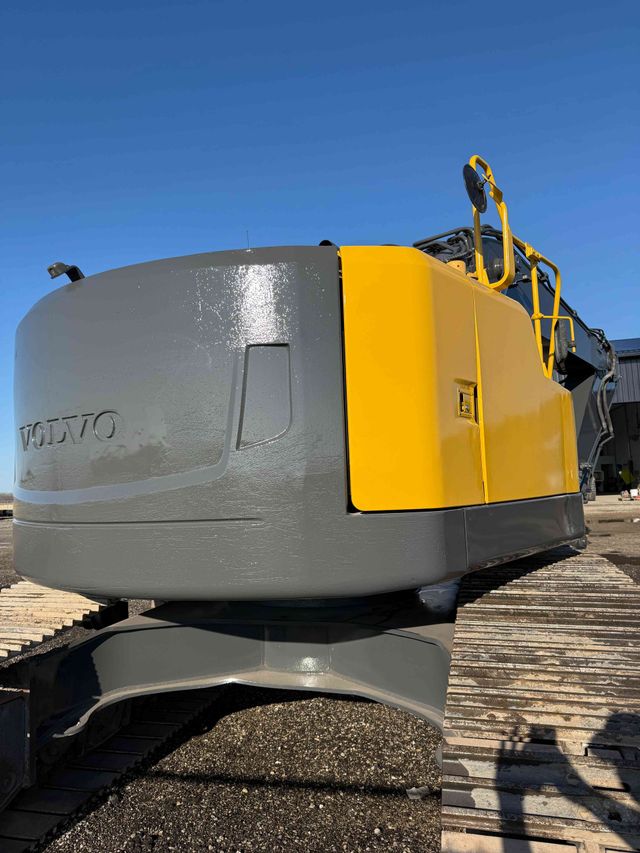 Yellow and gray construction machine on a rocky site under a clear blue sky