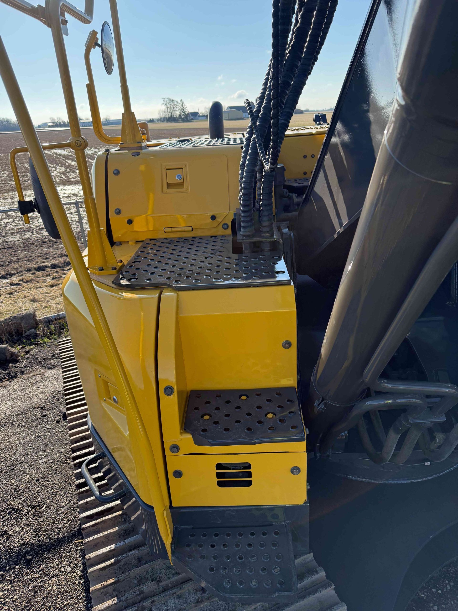 Yellow industrial stairs and platform on heavy equipment outdoors in a snowy worksite.