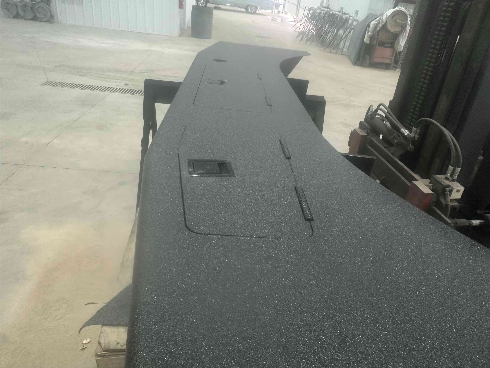 Black curved conveyor belt in an industrial yard, with a small control panel on top.