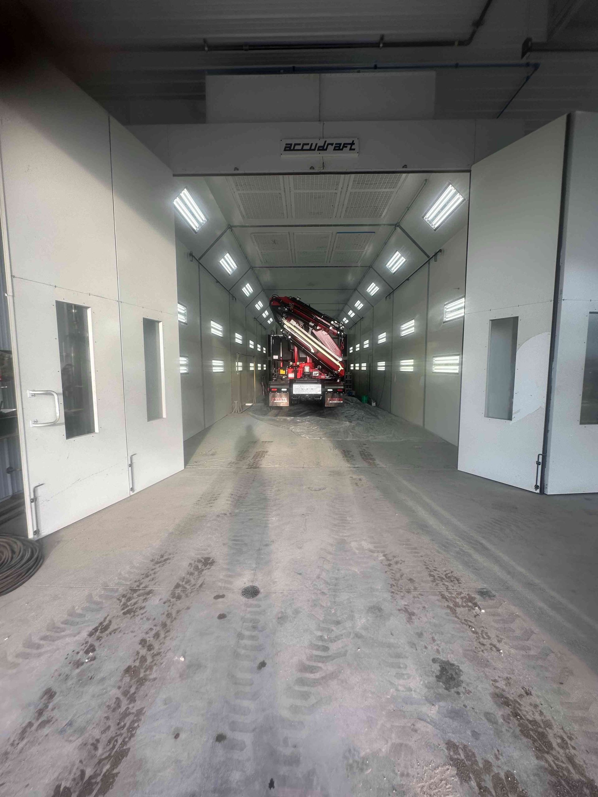 Truck inside a bright industrial wash bay with white walls and wet floor