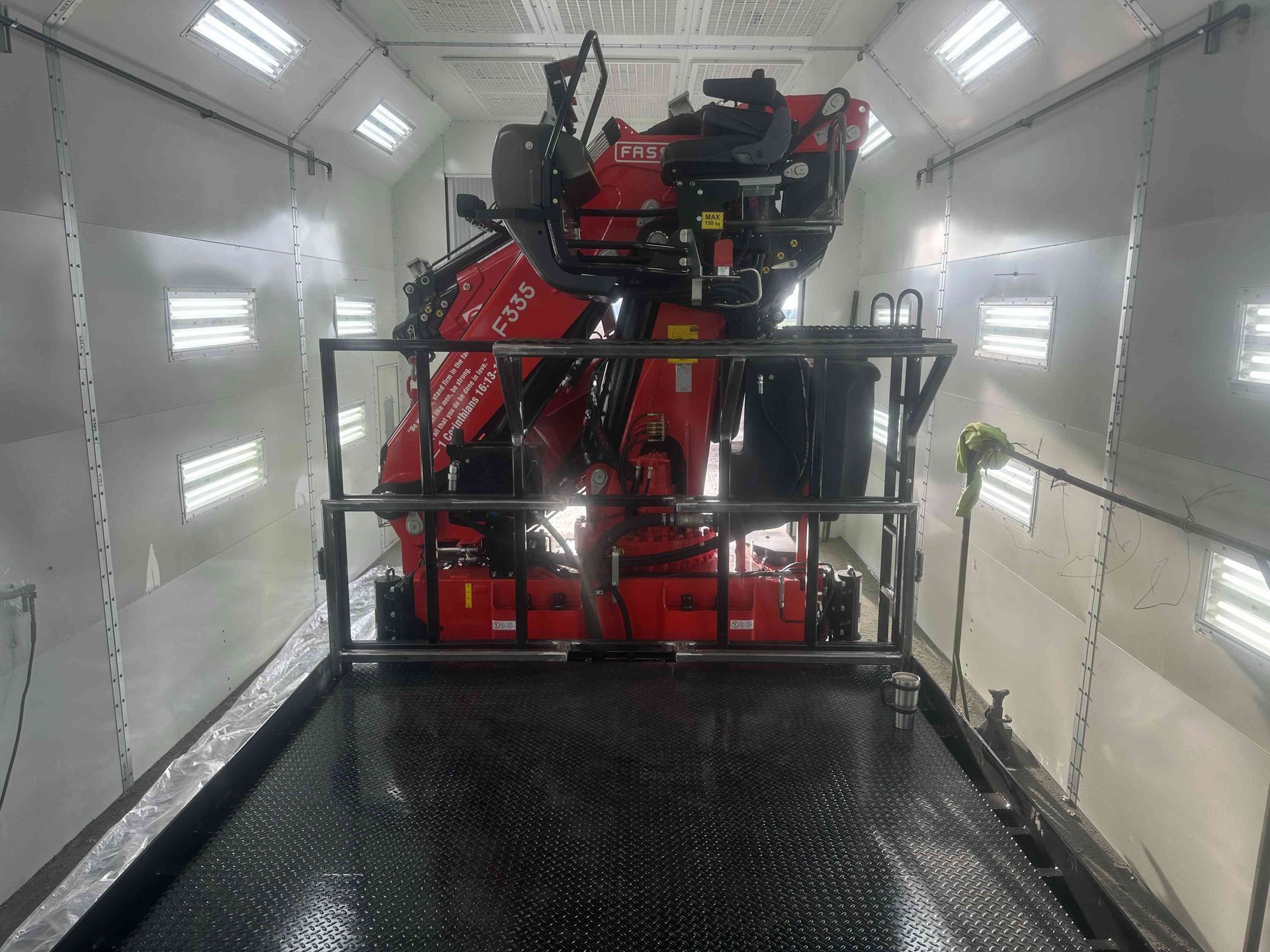 Red industrial machine inside a white, lit cargo trailer with a black metal floor platform.