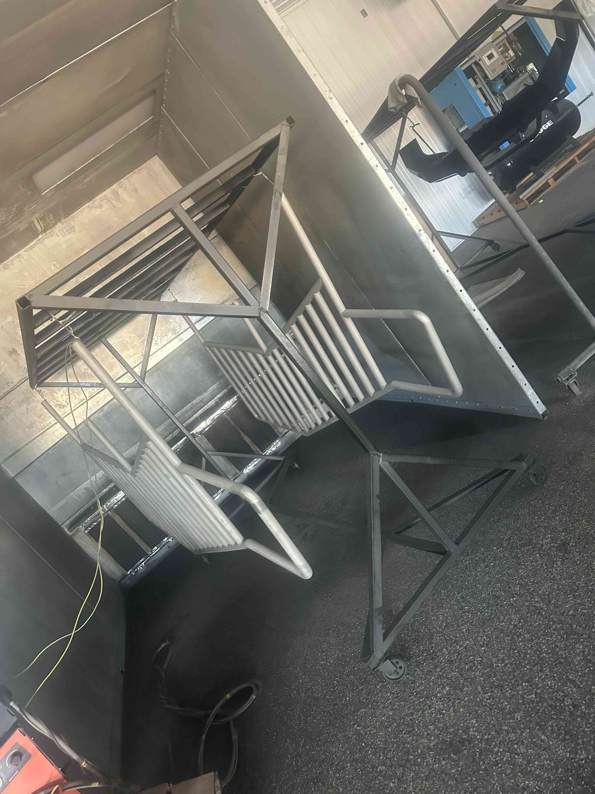 Industrial room with stacked metal drying racks and a blue machine on the right