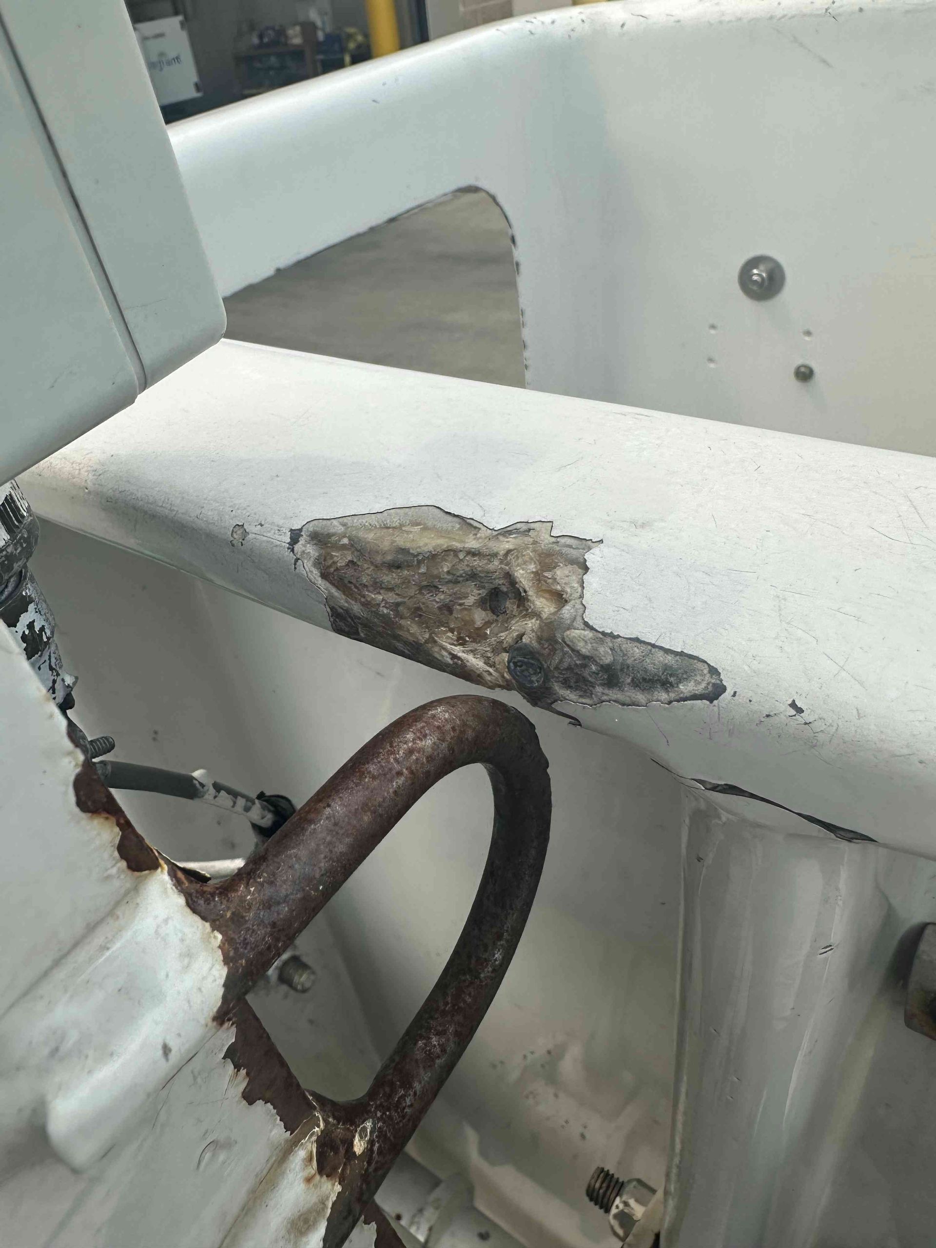 Damaged white railing with a rusted chain and chipped paint on a boat deck