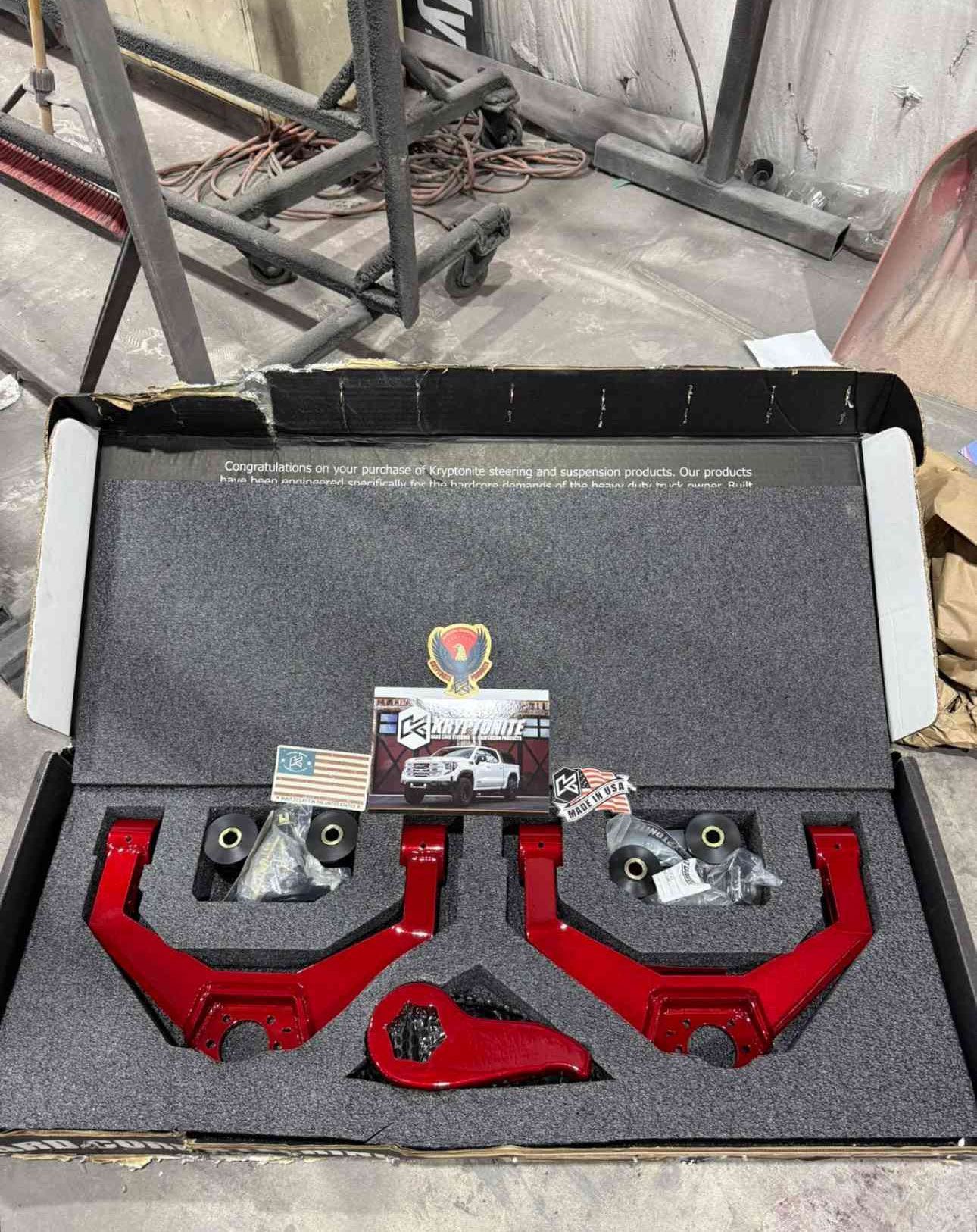 Open case with three red metal parts and hardware on black foam lining