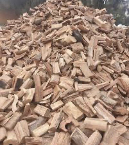 Pile of chopped firewood sticks in a container, light brown wood pieces stacked together.