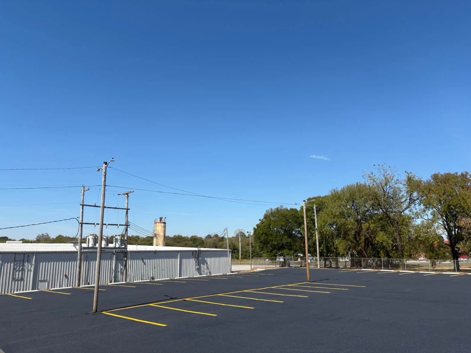 Empty parking lot beside a chain-link fence under a clear blue sky