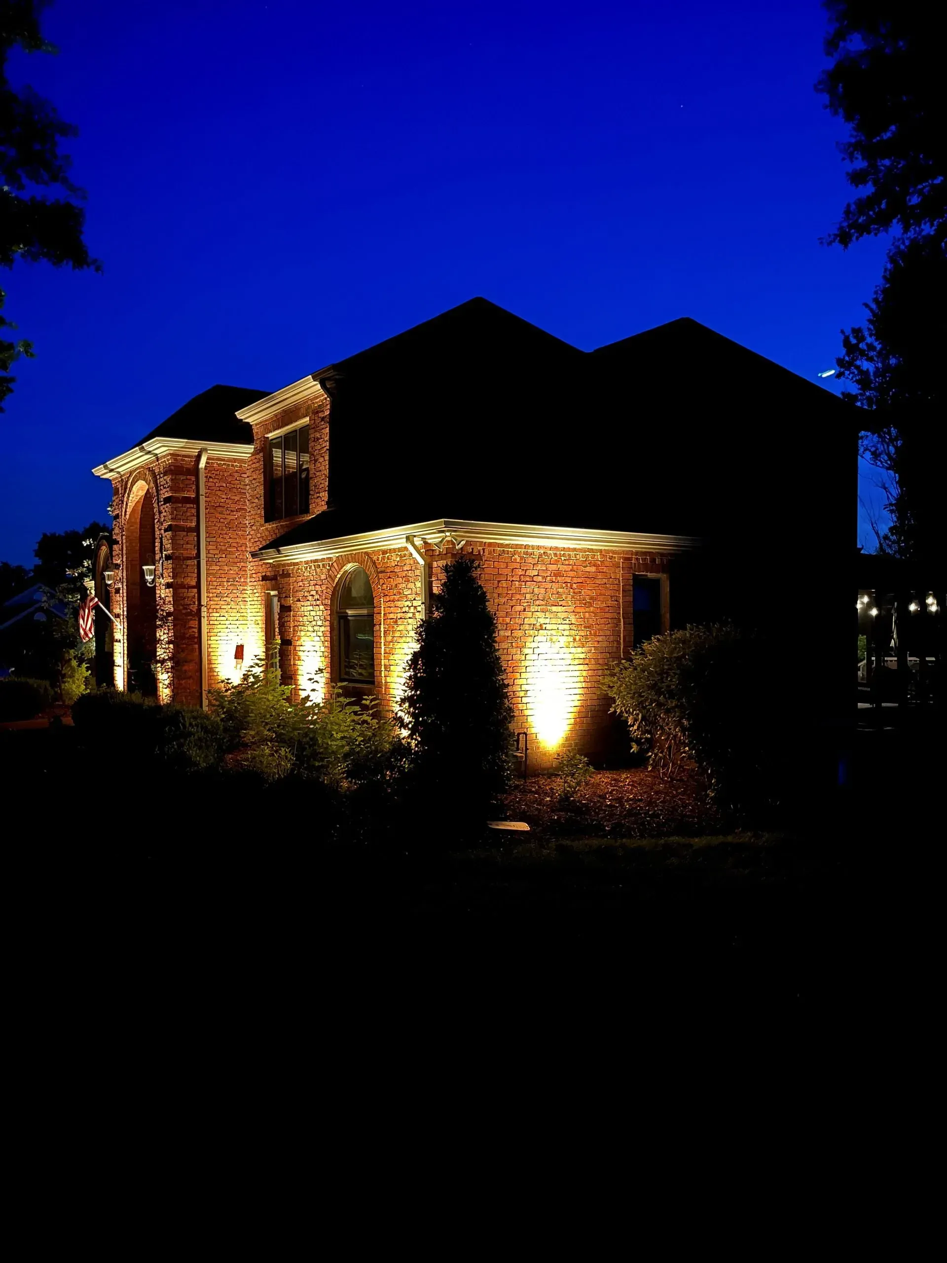 Brick house illuminated by outdoor lighting at night.