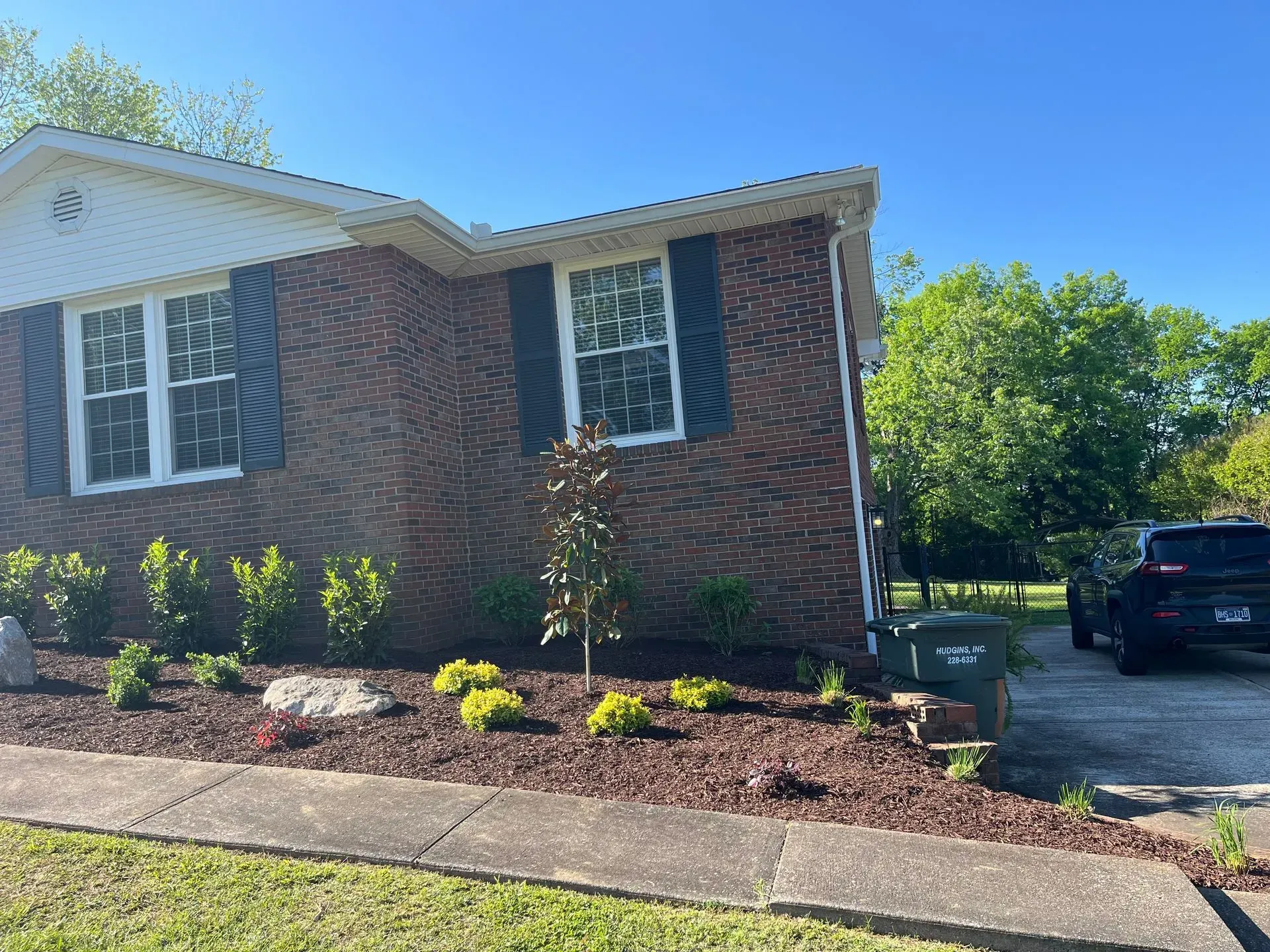Brick house with landscaped yard and dark green shutters on windows; black pickup truck in the driveway.