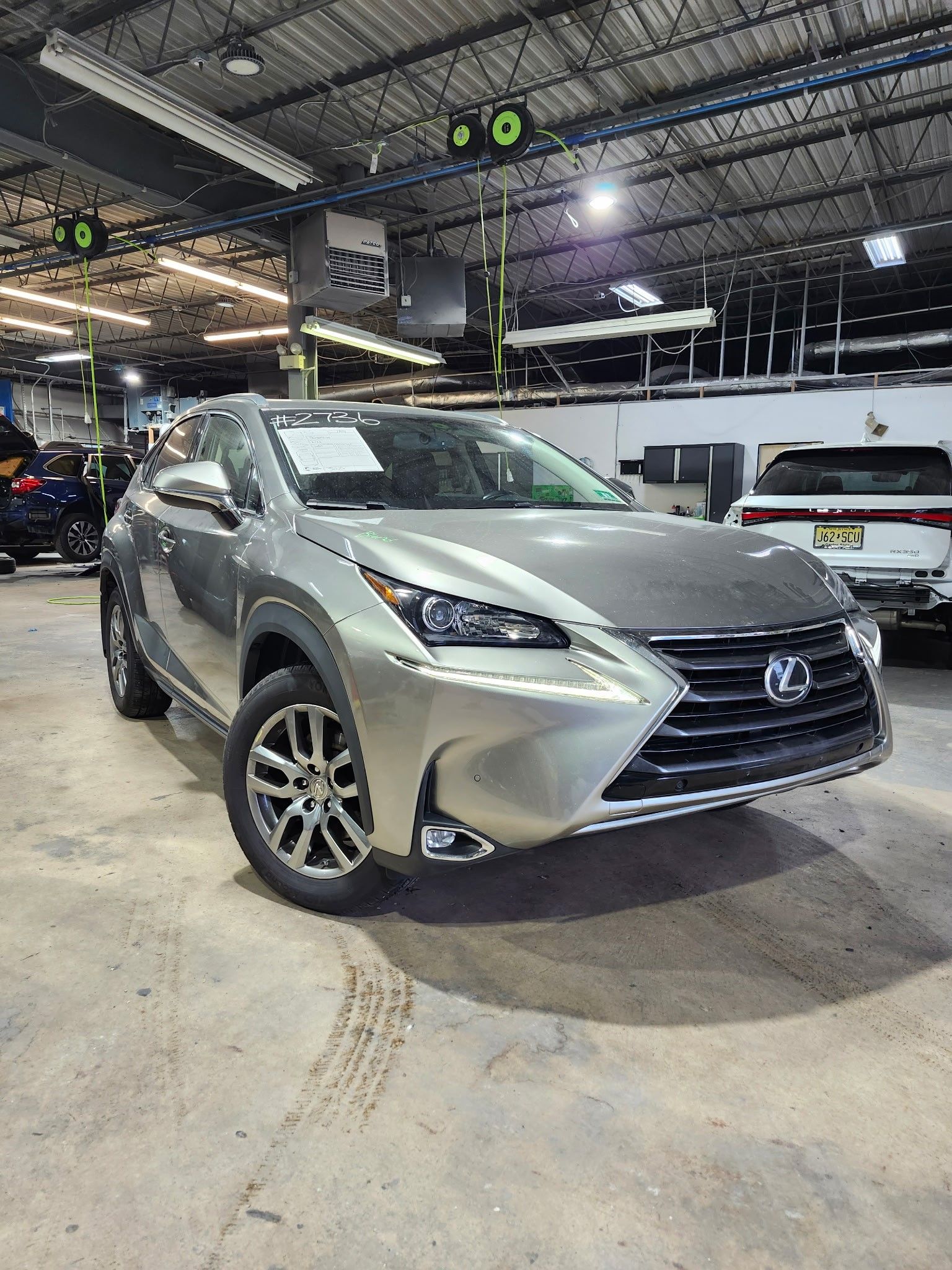 A silver lexus nx300h is parked in a showroom.