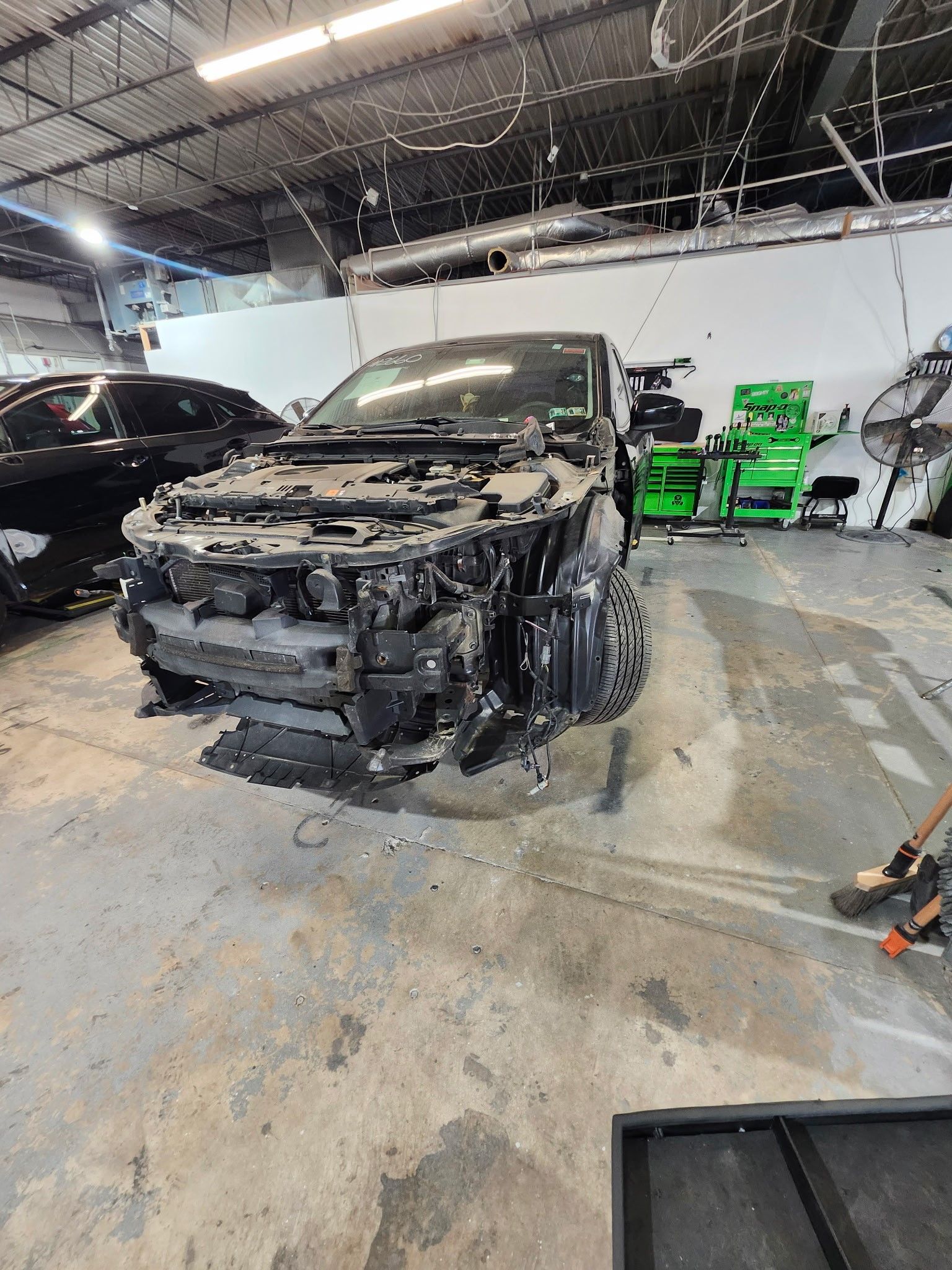 A car is sitting in a garage with its hood removed.