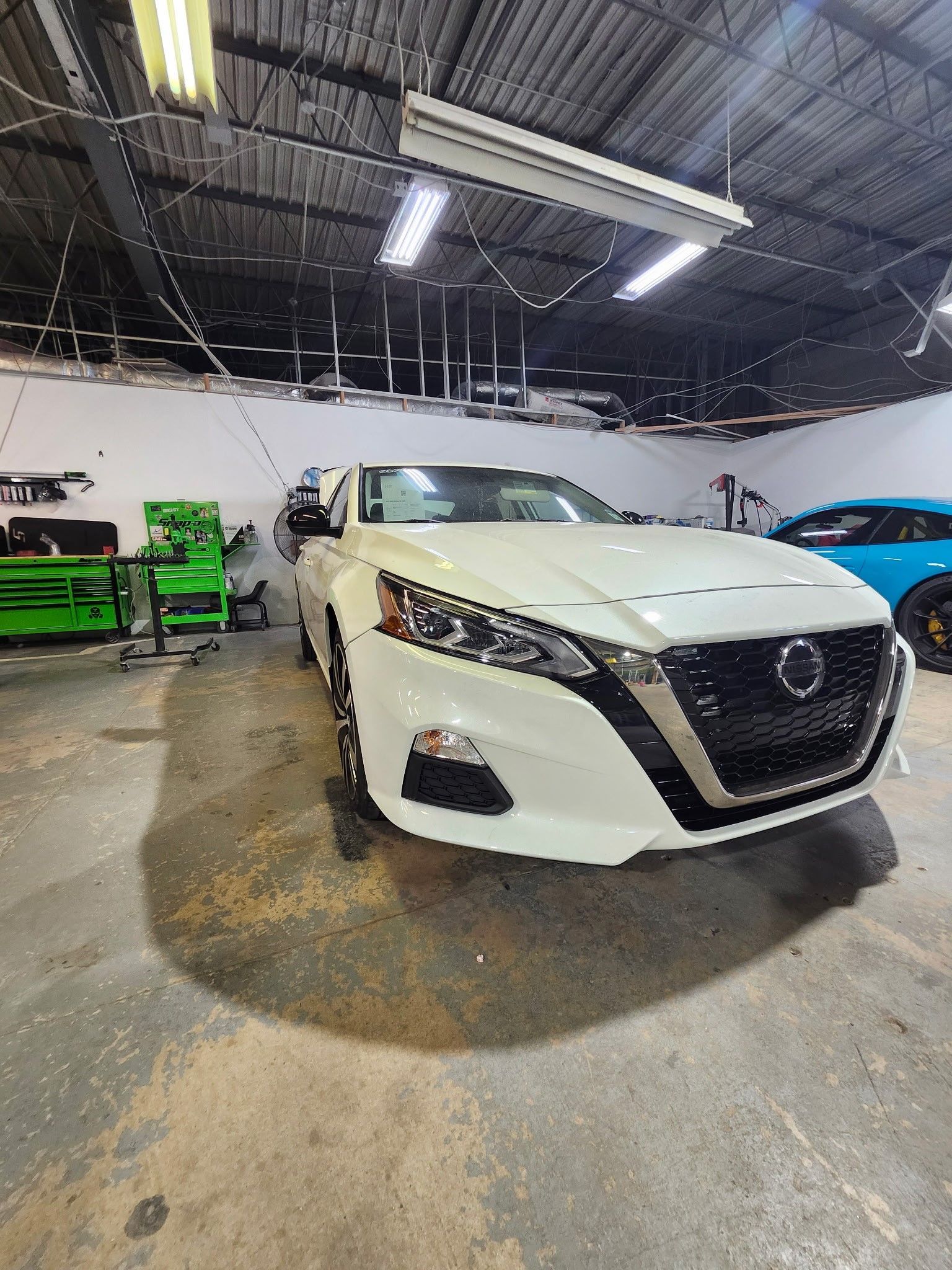 A white nissan altima is parked in a garage.