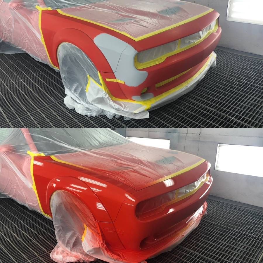 A red car is being painted in a paint booth