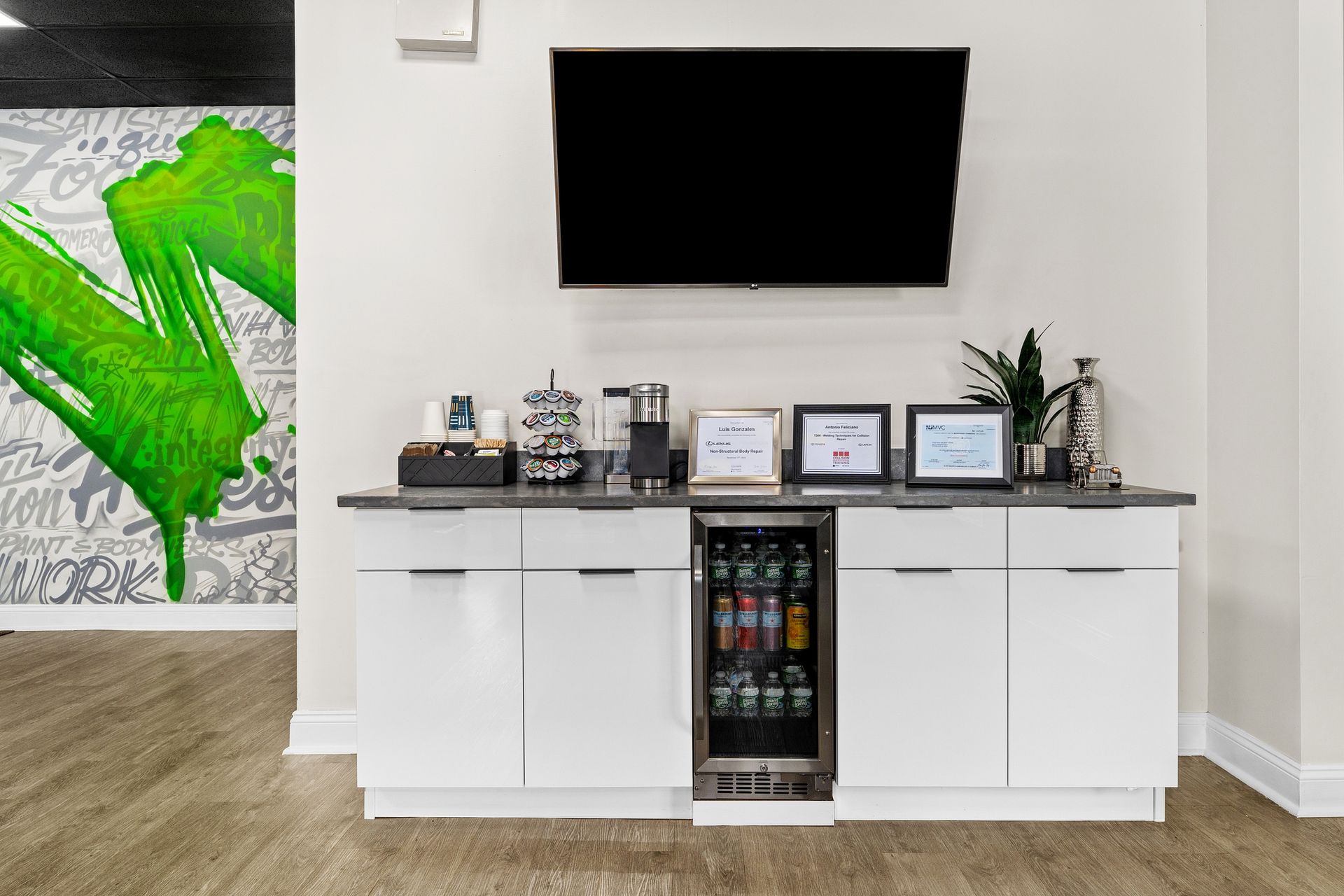 A kitchen with a refrigerator and a flat screen tv on the wall