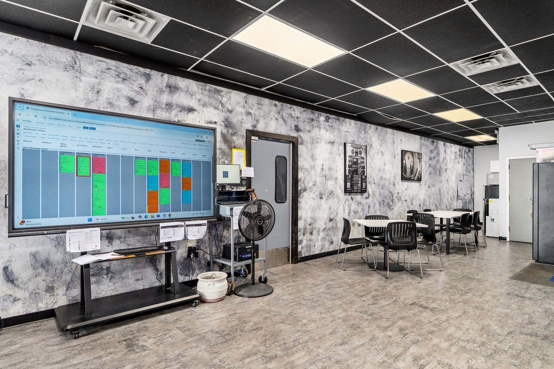 A large room with tables and chairs and a large screen on the wall