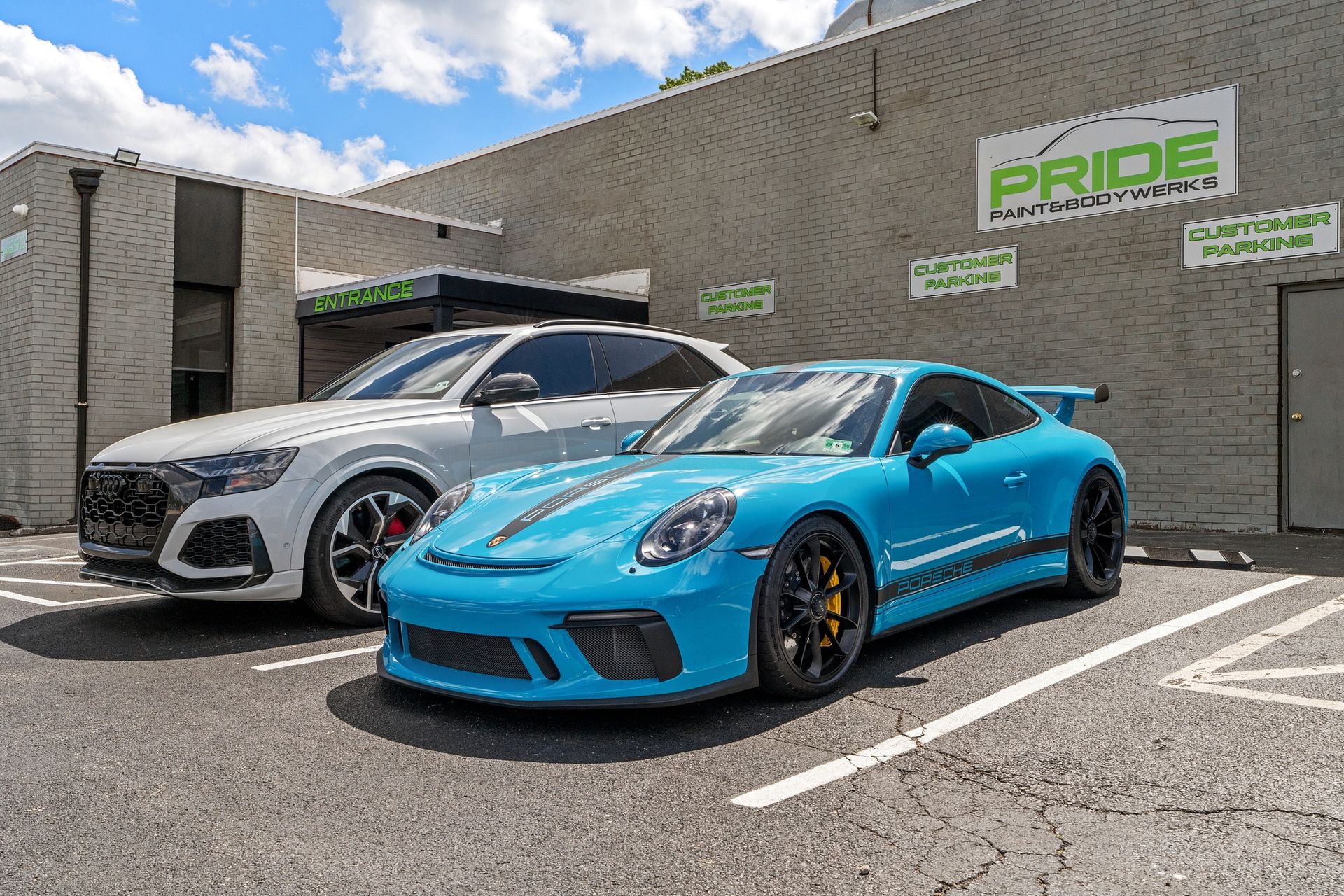 Two sports cars are parked in a parking lot in front of a building