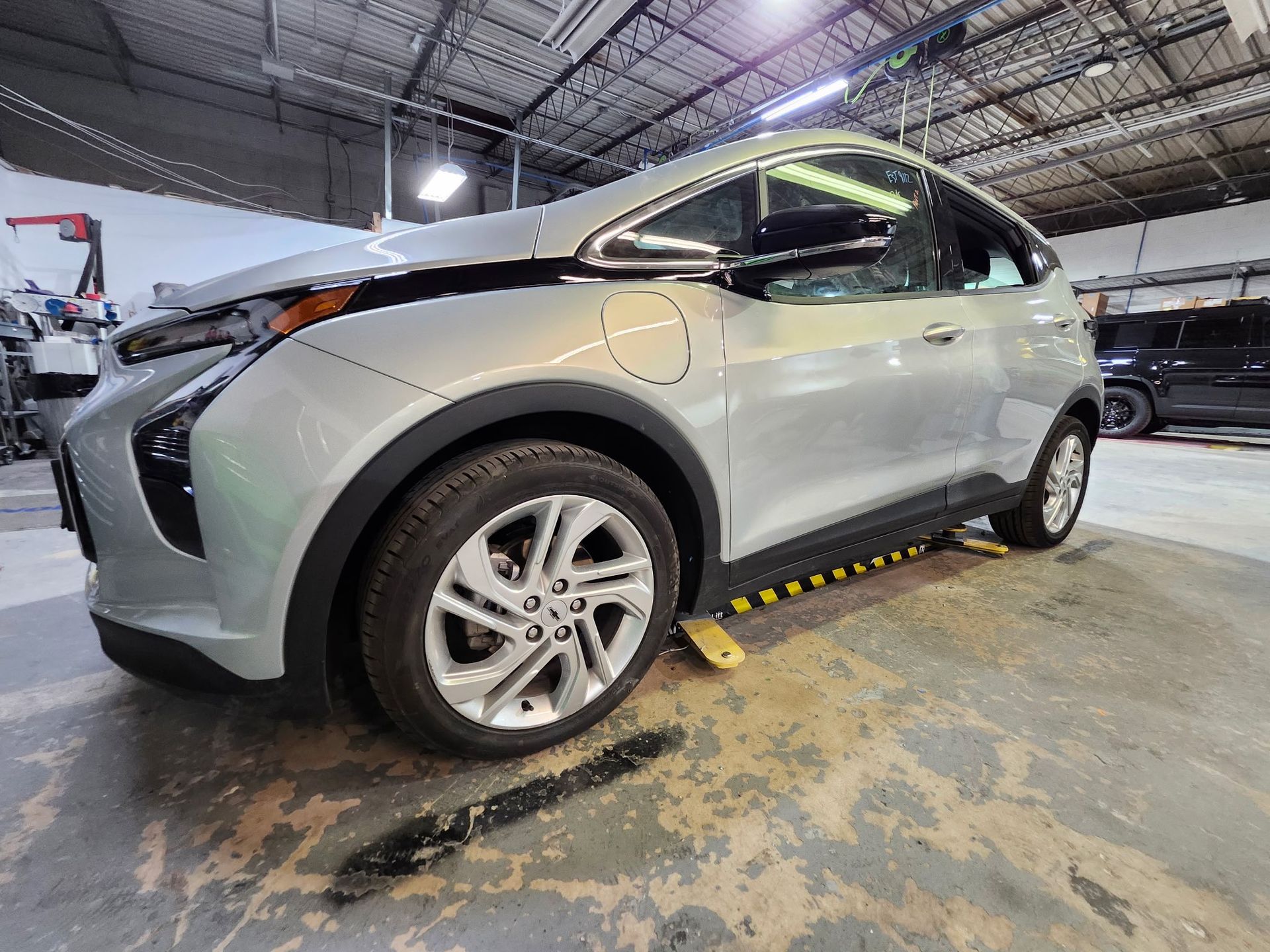 A silver car is sitting on a lift in a garage.