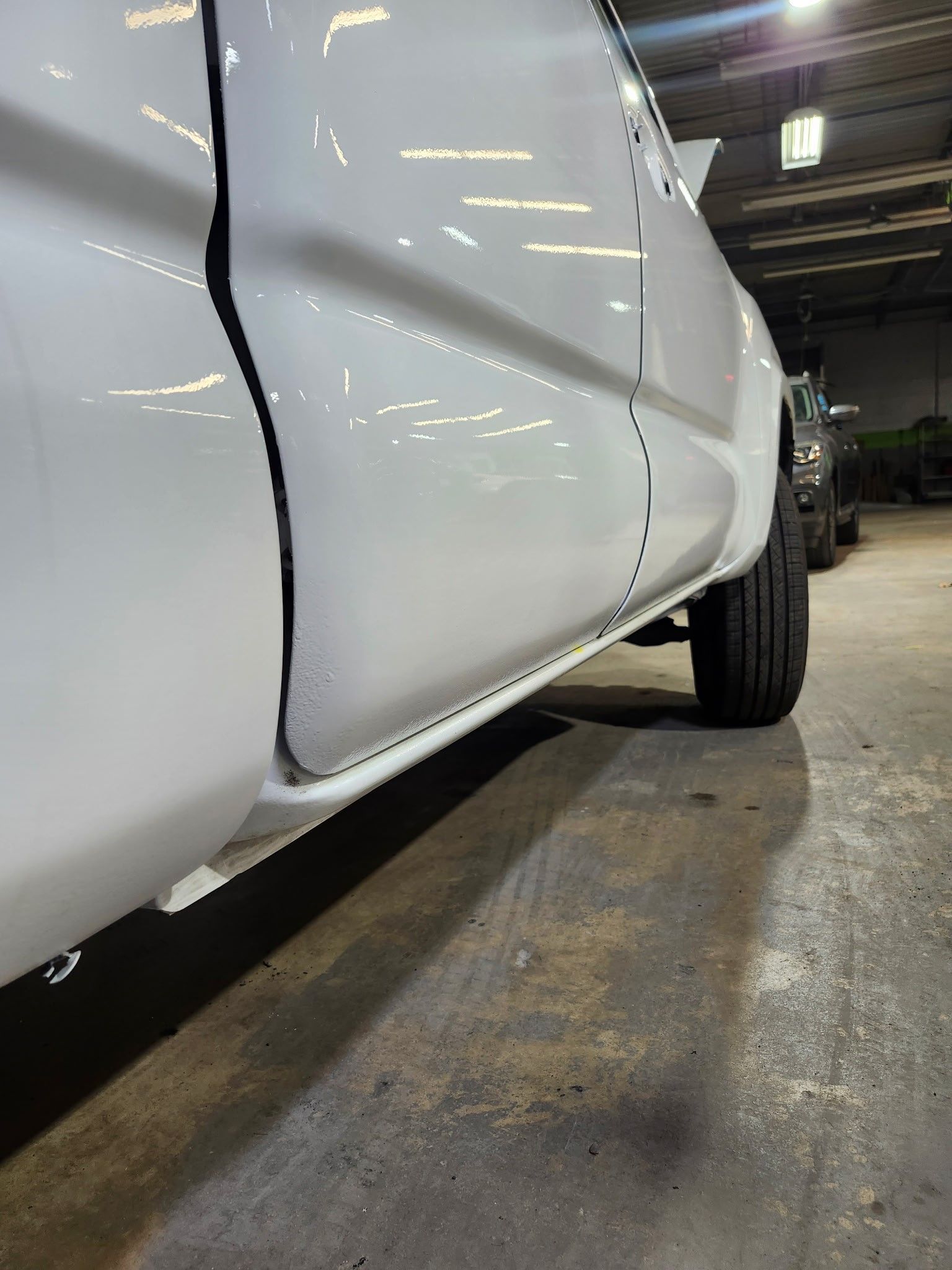 A white truck is parked in a garage with the door open.