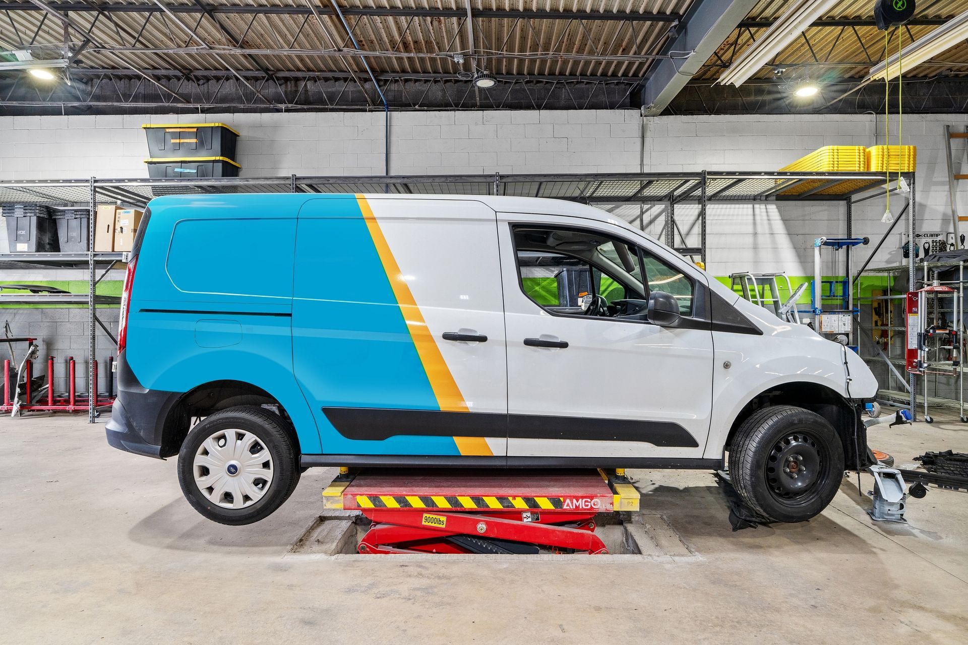 A blue and yellow van is sitting on a lift in a garage
