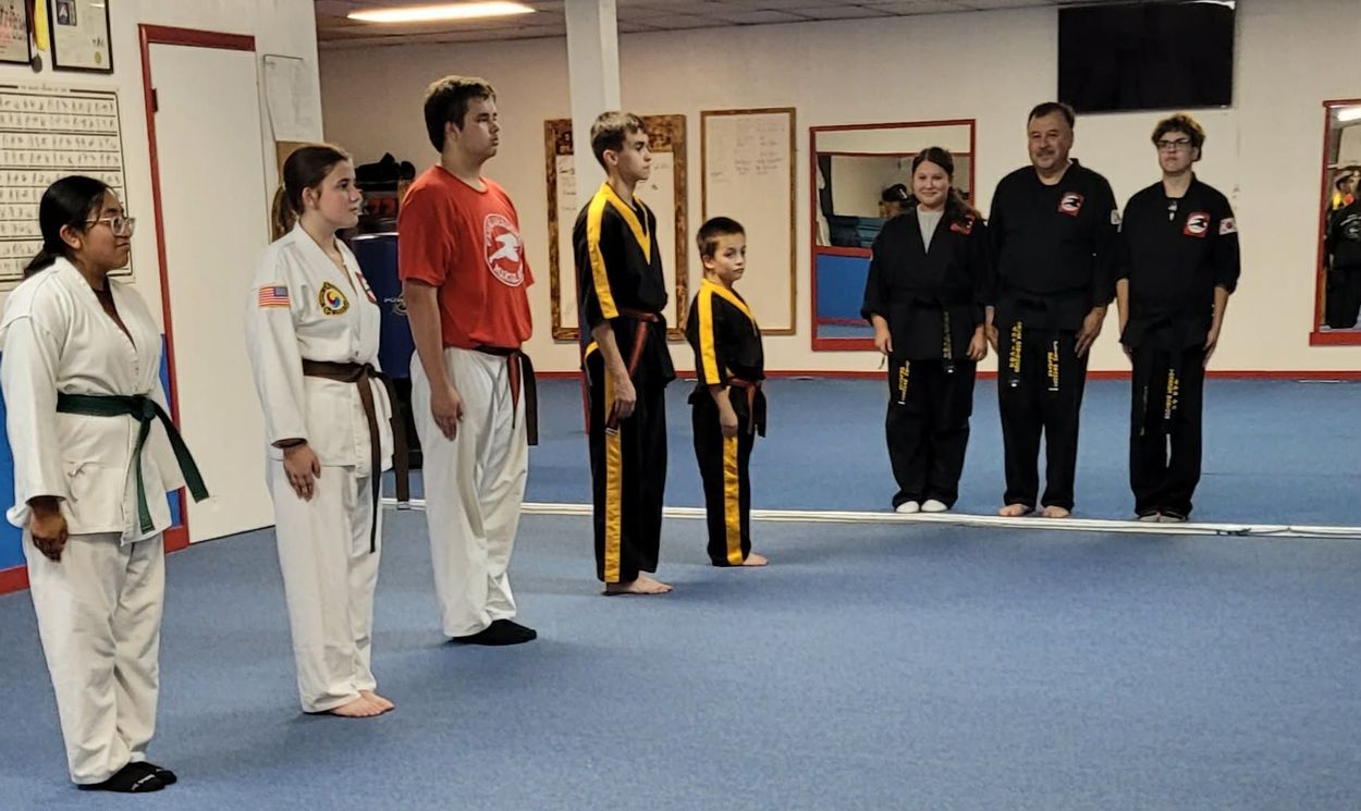 Martial arts students standing in line with instructors in a training studio