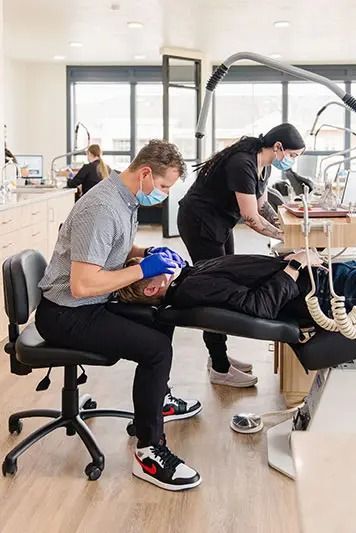 Orthodontist and assistant working on a patient's teeth in a clinic.