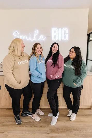 Four people in hoodies smile near a 