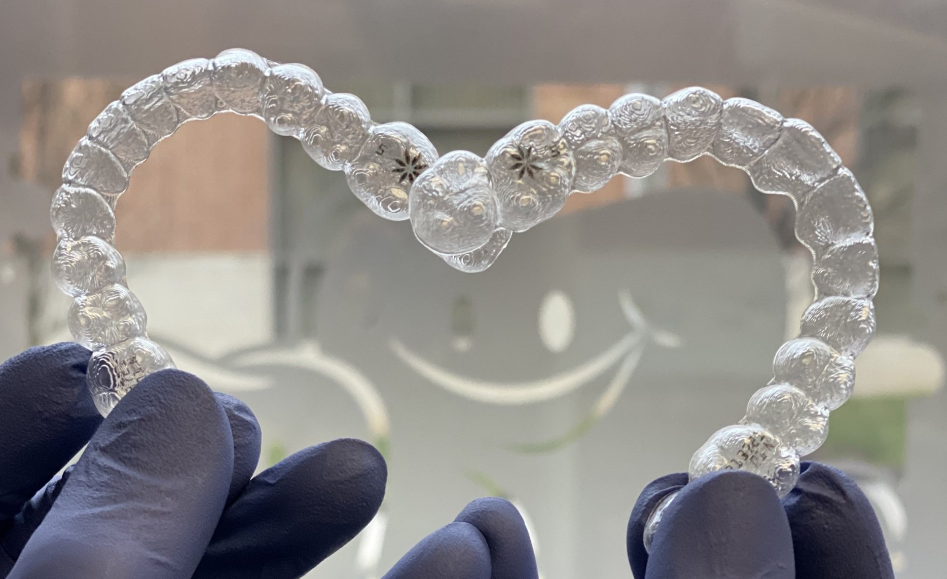 Clear aligners from Invisalign being held up to the window at Nurture Dental Health in Allentown, PA.